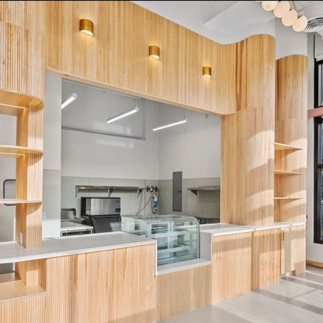 Wood-paneled cafe interior under construction with built-in shelving and a service counter