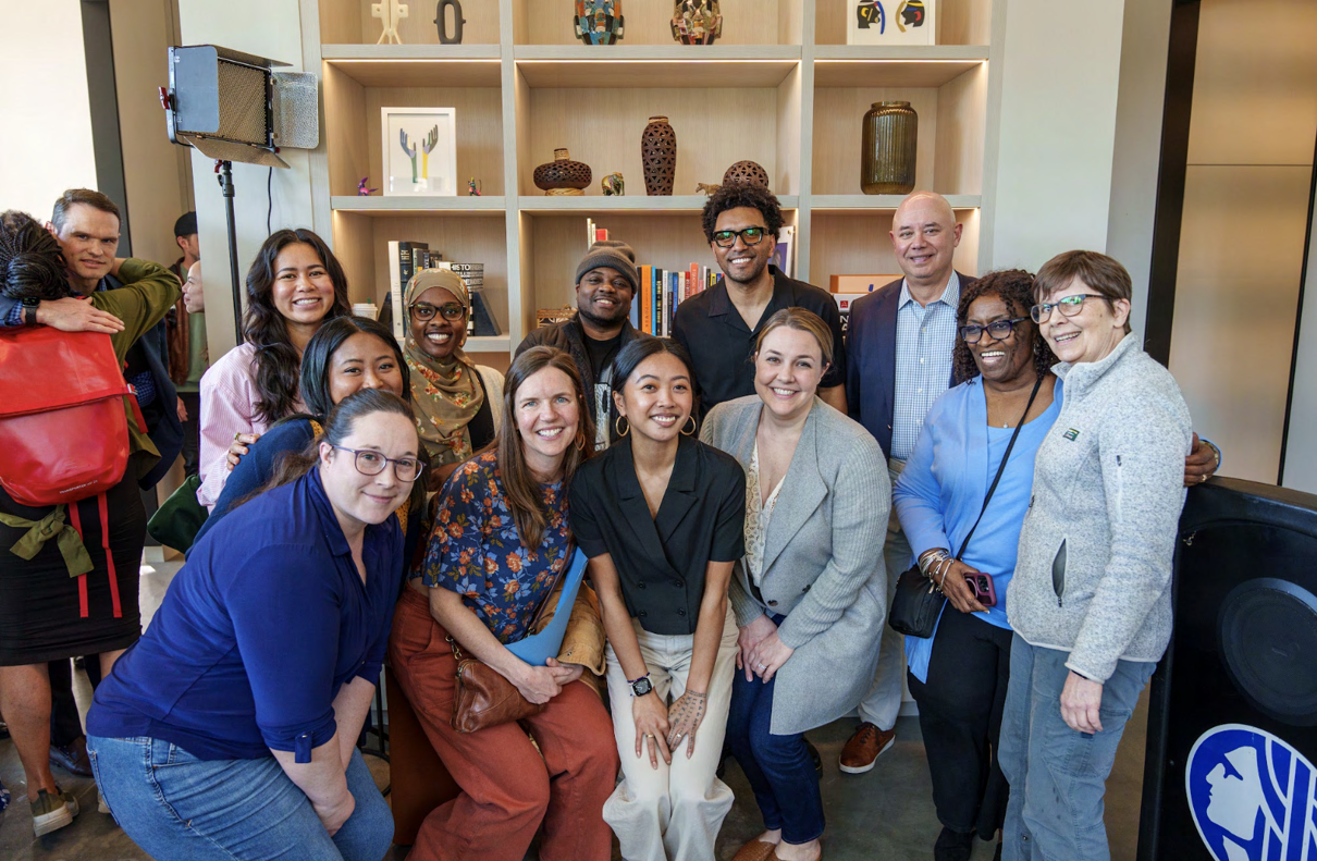 Large group of about thirteen people posing together indoors for La Union Studio's grand opening event, including Seattle city officials