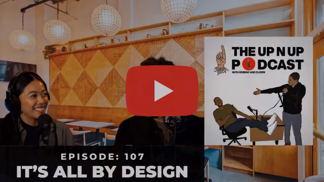 Video thumbnail showing a woman speaking into a microphone in a studio, with text reading 'Episode 107: It's All By Design'