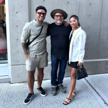 Oscar Rodriguez standing between two people outside a concrete building