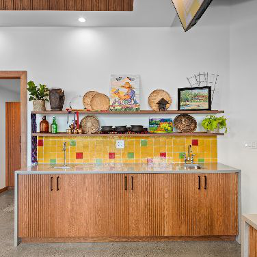 CheBogz Filipino Food interior showing a wood counter with yellow tile backsplash and shelving displaying decorative objects and plants