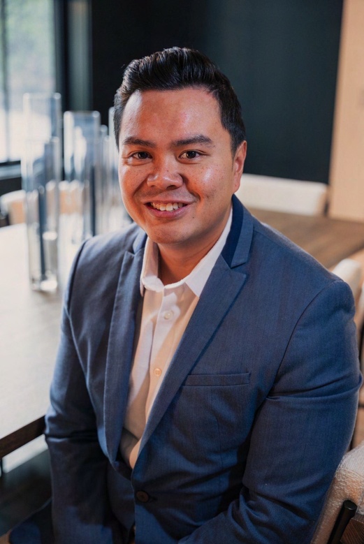 Headshot of Albert Solis, Director of Business Development, wearing a navy blazer over an open-collar shirt and smiling at the camera in a bright interior.