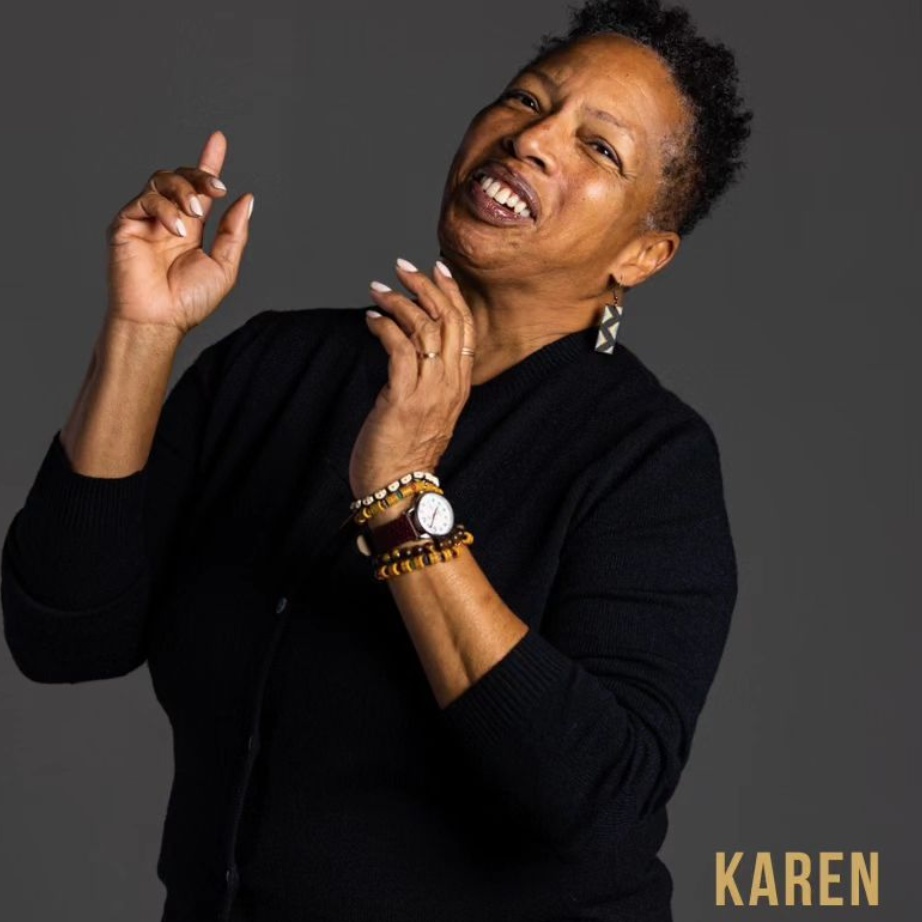 Karen Toering of Black & Tan Hall, wearing a black jacket and stacked gold bracelets, laughing with her hands raised expressively against a dark grey backdrop, with her first name set in gold lettering in the lower corner.