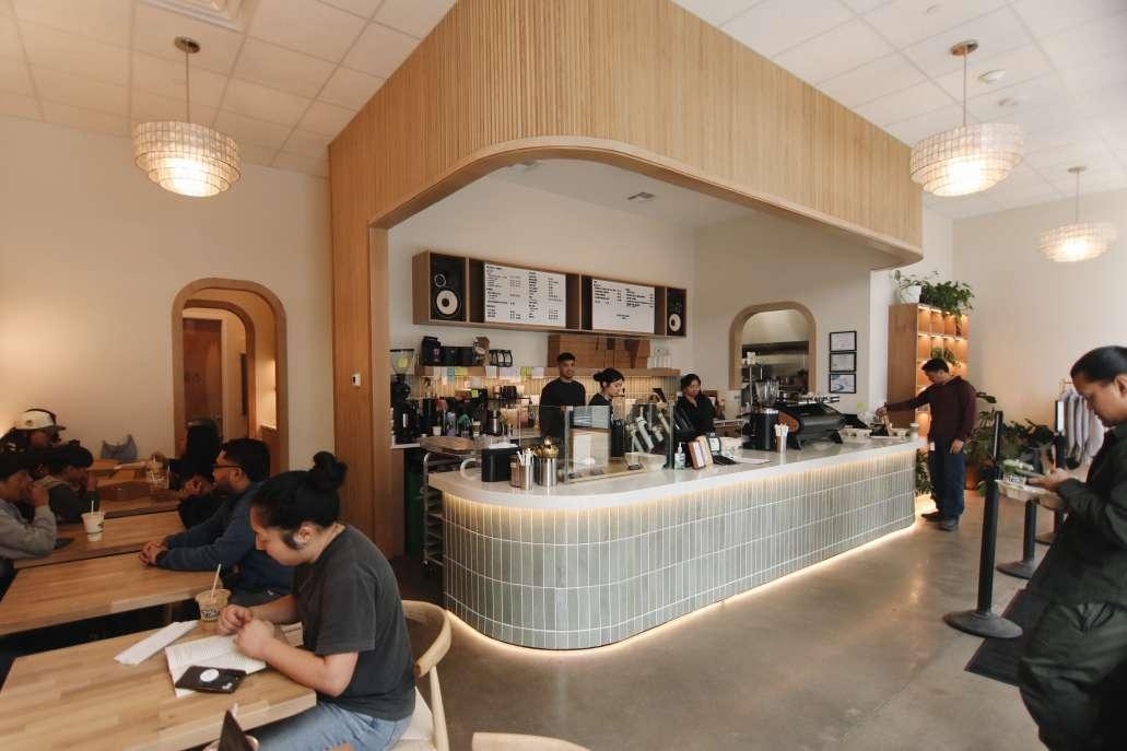 Ayala Coffee counter and wood-paneled display shelves styled with plants, books, and decor