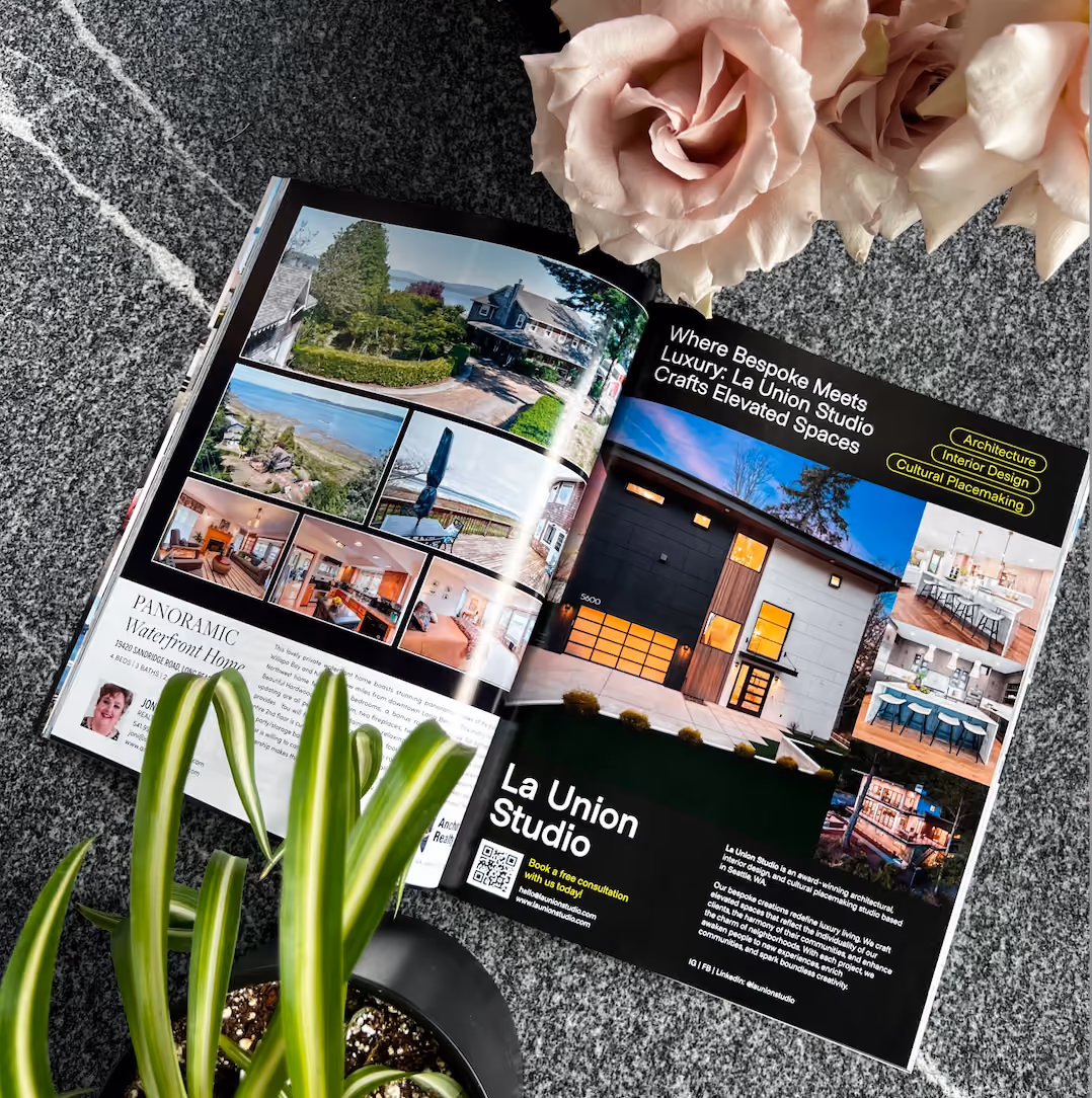 An open copy of HAVEN Lifestyle Magazine resting on a speckled stone surface beside pale roses and a potted plant, showing a two-page feature on La Union Studio with photographs of a waterfront home and interior projects.