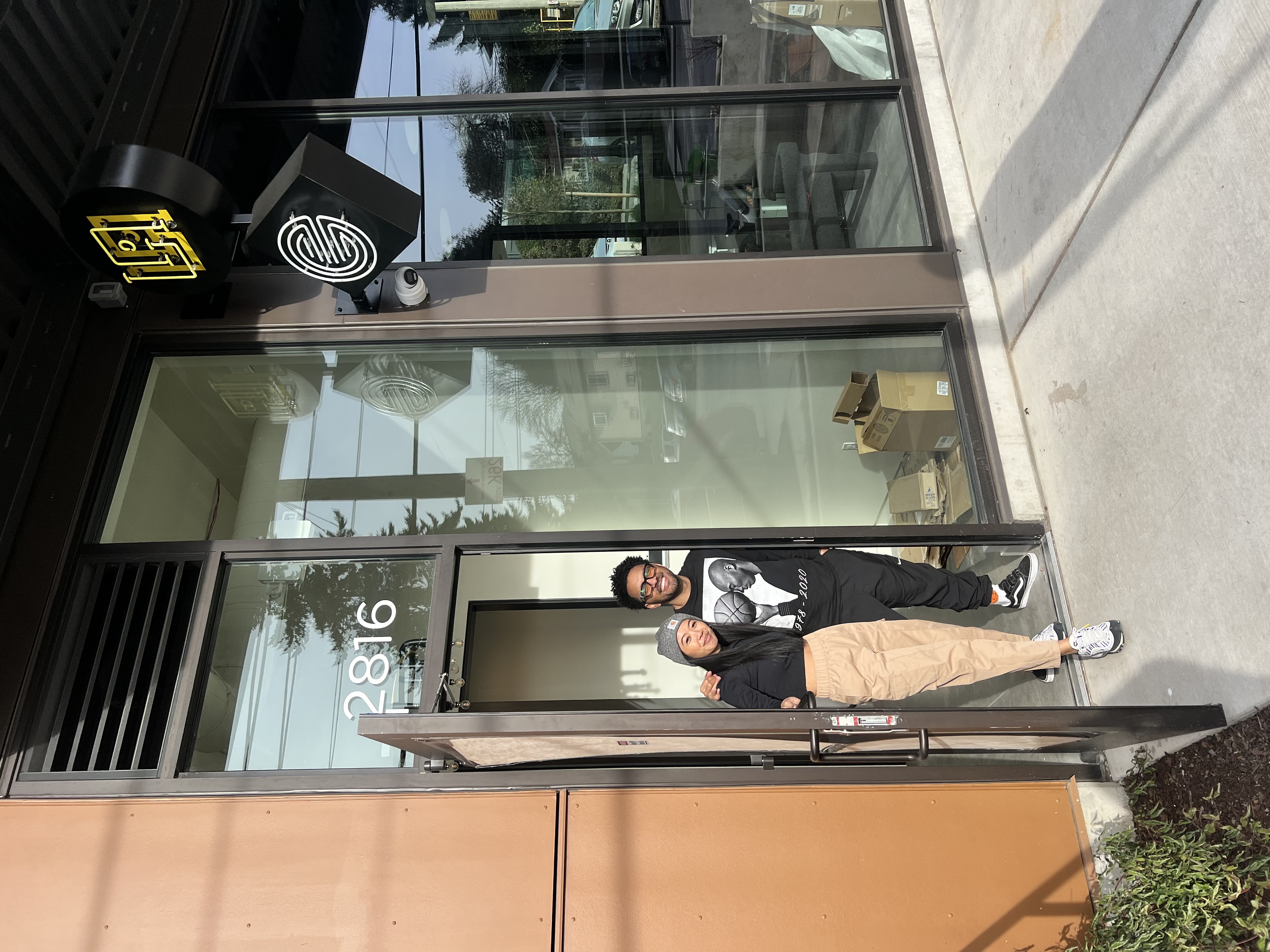 Sonia-Lynn and a colleague standing together in the doorway of the new Emblem Skincare storefront, marked with the address '2816' and the La Union Studio logo above