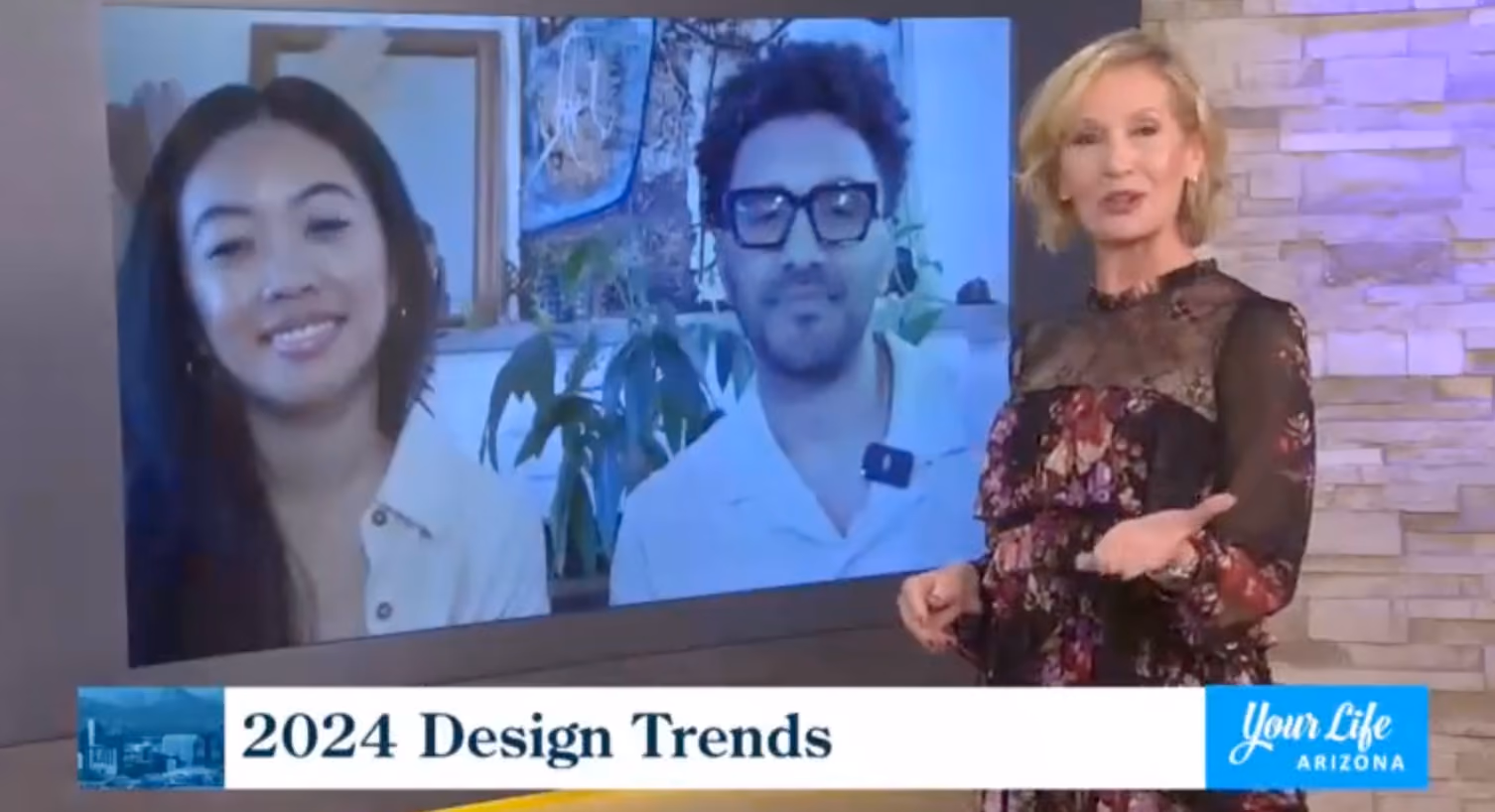 A television segment in progress: a host in a floral lace dress gestures toward a large screen showing two La Union Studio team members on a video call, with a lower-third graphic reading "2024 Design Trends" and the Your Life Arizona logo.