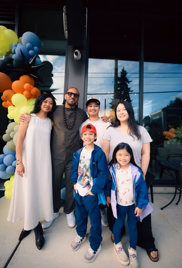 Family of six posing together outdoors in front of the balloon-decorated entrance