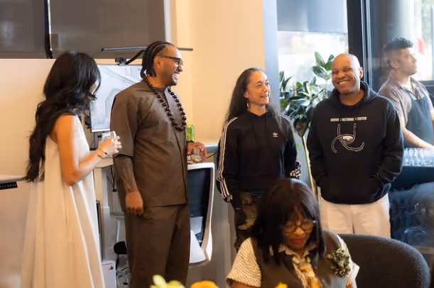 Five people posing together and smiling at the open house