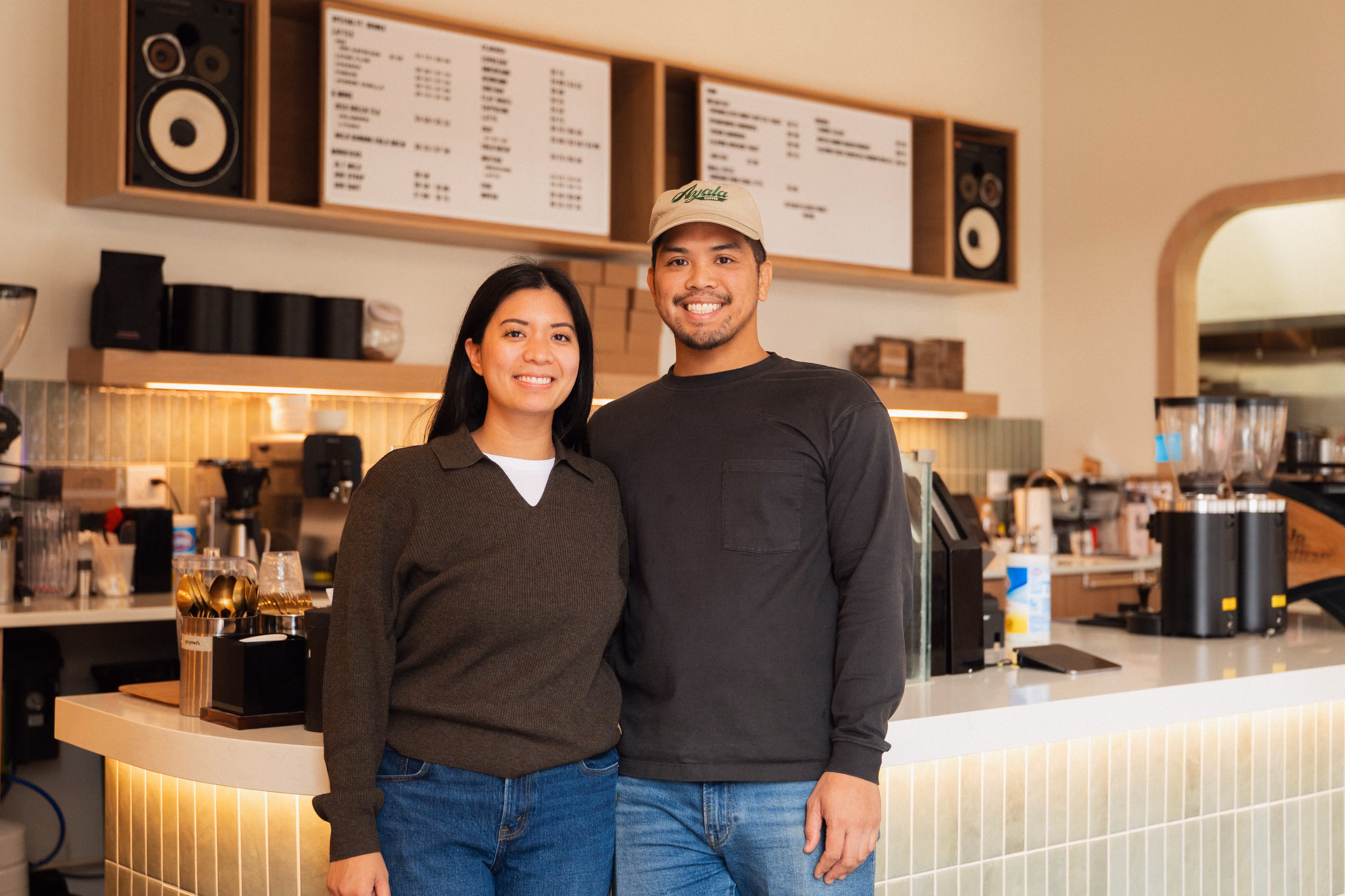 Two Ayala Coffee staff members smiling together behind the counter