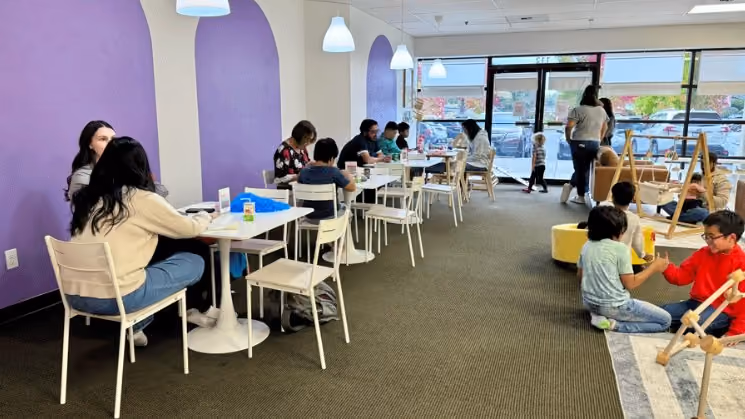 Families and children gathered at tables in a purple-accented room at Laro Tayo