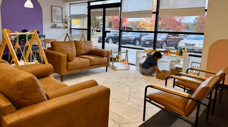 Leather armchairs and a couch in a lounge area at Laro Tayo, with a play structure visible in the background