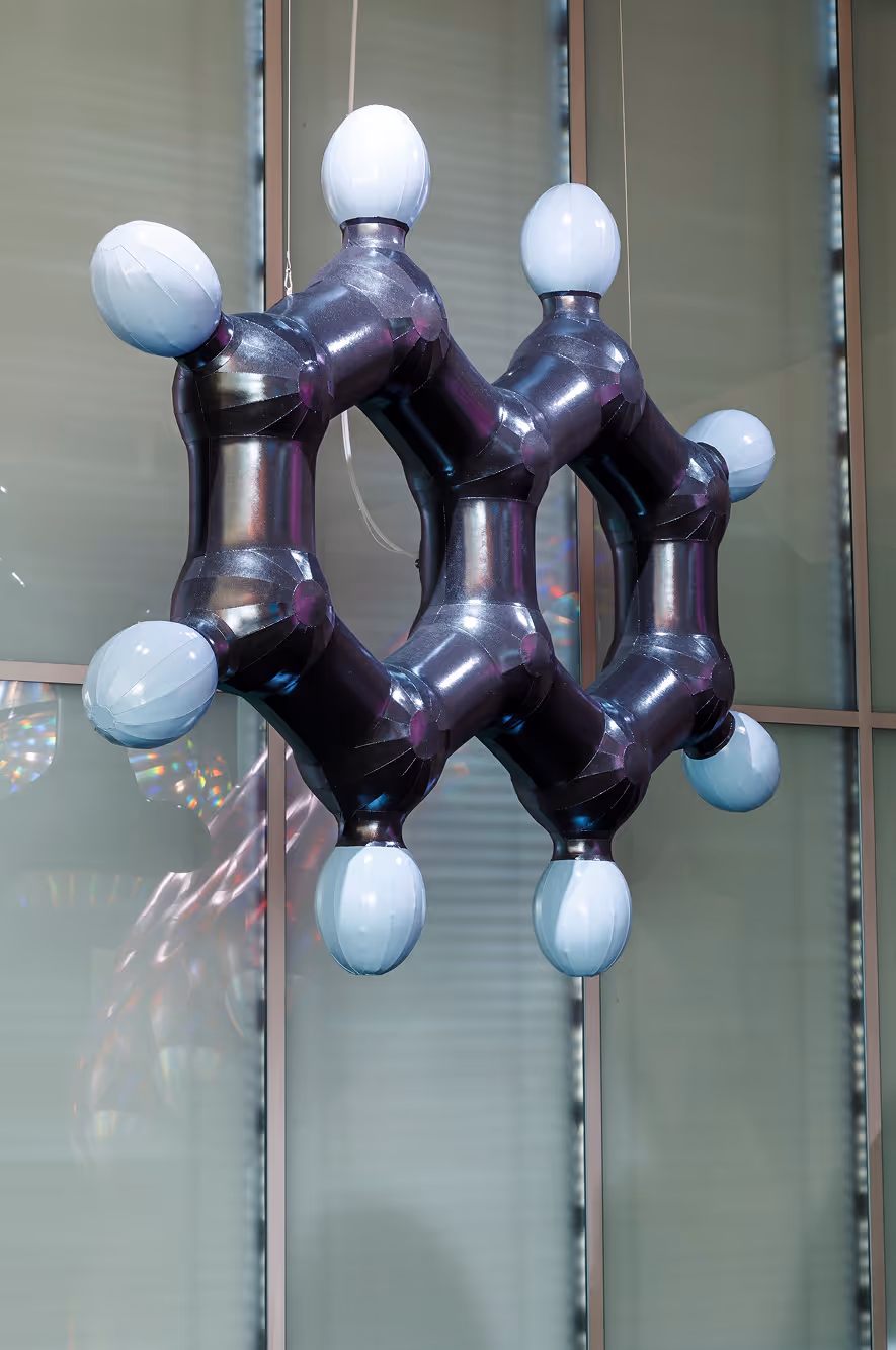 Stor oppblåsbar molekylmodel i sort med hvide kugler, hængende foran vinduer.