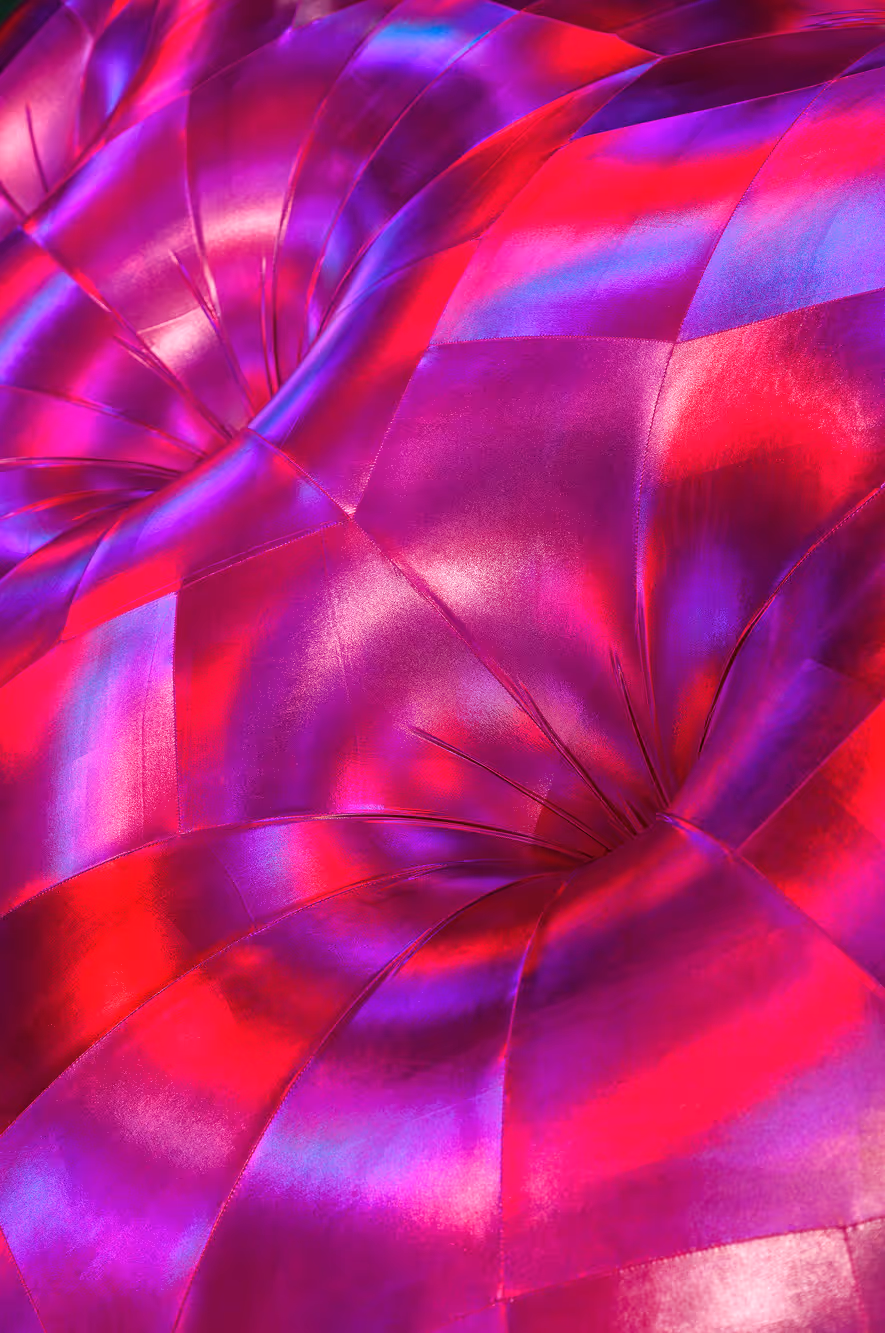 Nærbillede af en skinnende rødlilla patchwork-tuftet pude med reflekterende stof.