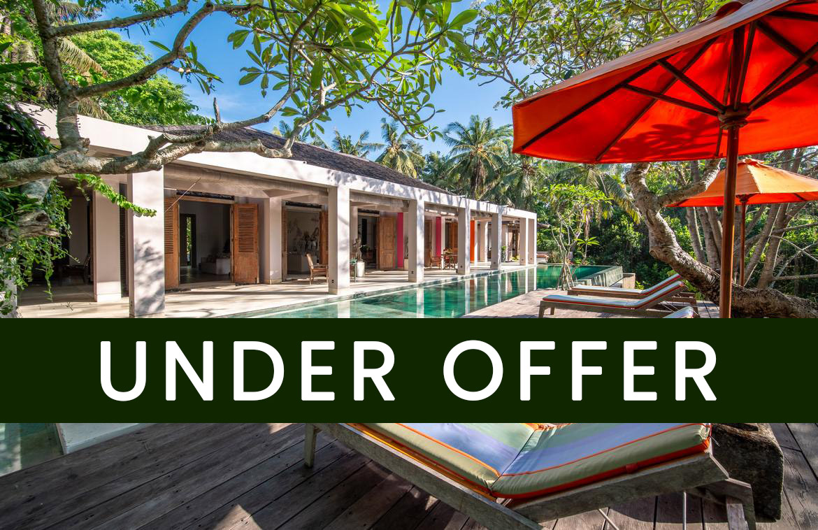 Set on a sprawling 4,000 sqm terraced landscape that cascades down to a majestic river, this architectural masterpiece is a standout creation. Designed by the late renowned Terry Brooks, as his private residence,every element reflects the heart and vison of this amazing designer.‍Nestled in the tranquil village of Nyambu, this property is surrounded by nature yet enjoys convenient access to Bali's hotspots—just a short drive to Canggu in the south and less than an hour to Ubud in the north.‍The estate comprises four distinct buildings:‍1. The Main ResidenceA blend of modern colonial charm and elegant design, the main building boasts high-pitched wooden ceilings that create an airy, grand ambiance. Antique double teak doors and a covered patio running the length of the building add timeless character.Central Lounge: A cozy lounge anchors the space, flanked by a 10-seater dining area on one side and a TV lounge on the other.Patio Dining: Two round dining tables on the patio offer an al fresco dining experience with views of the pool and jungle beyond.Swimming Pool & Deck: The expansive 18m infinity pool is complemented by a large wooden deck outfitted with daybeds, perfect for sunbathing or relaxing in the serene surroundings‍‍2. The Master Bedroom PavilionThis private retreat includes a spacious terrace, a built-in wardrobe, and a luxurious semi-open bathroom. Adjacent to the suite is a dedicated spa room complete with a massage table and a terrazzo bathtub, offering a truly indulgent experience.‍3. Lower Level Waterfall PavilionThe estate's lower level houses a two-bedroom pavilion with en-suite bathrooms and serene views of lush greenery. ‍4. The Garden PavilionInspired by traditional Javanese Joglo architecture, this open-plan structure sits near the entry to the property and features three en-suite bedrooms, each spaciously designed and complemented by semi-open bathrooms. At the heart of the pavilion lies an inviting open living area, seamlessly connecting to lush gardens framed by coconut trees.‍At the bottom of the property, a stunning natural landscape meets the riverbank. An artificial waterfall cascades from the edge of the pool into a pond below, creating a tranquil focal point. This area also offers untapped potential for additional bedrooms or an entertainment space.‍This exceptional estate is ideal as a luxurious residence, a commercial villa rental, or a private venue, offering an unmatched combination of seclusion, style, and proximity to Bali’s vibrant destinations.