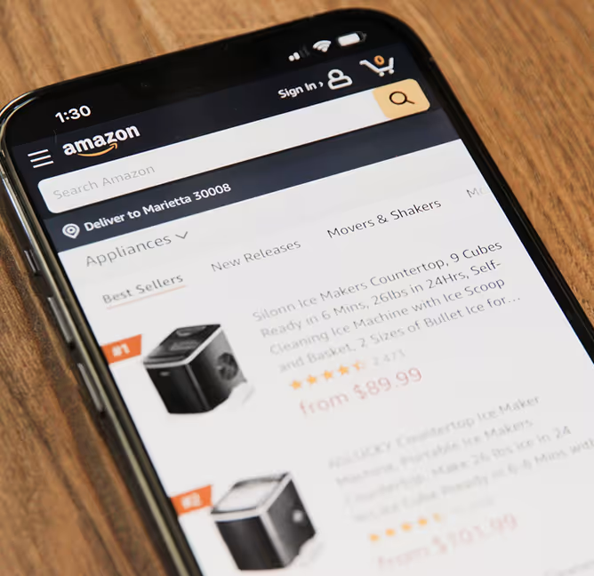 A cell phone displaying the amazon app on a wooden table.