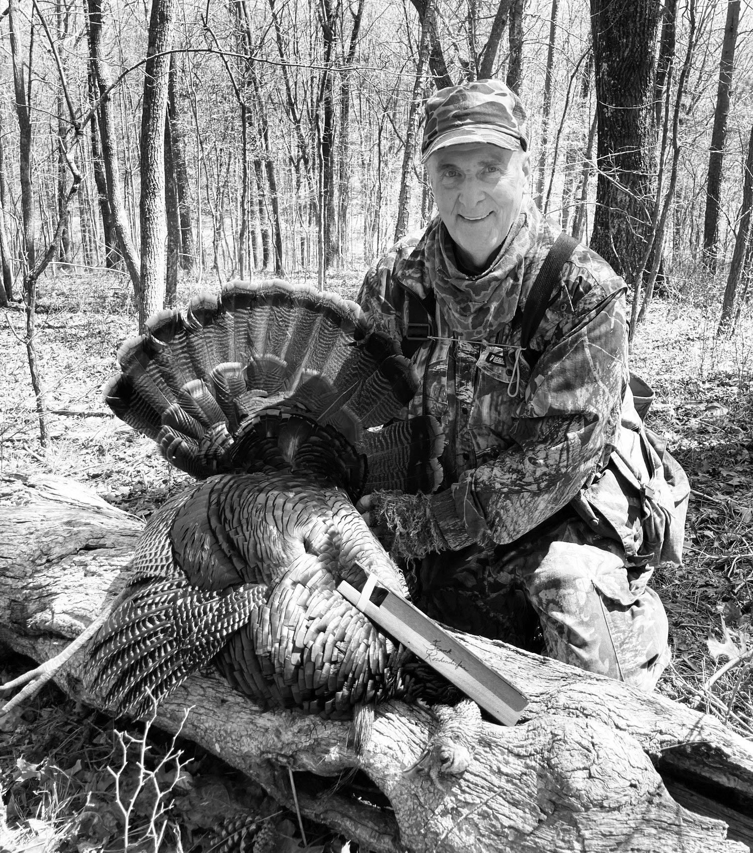 Black and white photo of Frank Kochenderfer holding a killed turkey with his turkey call