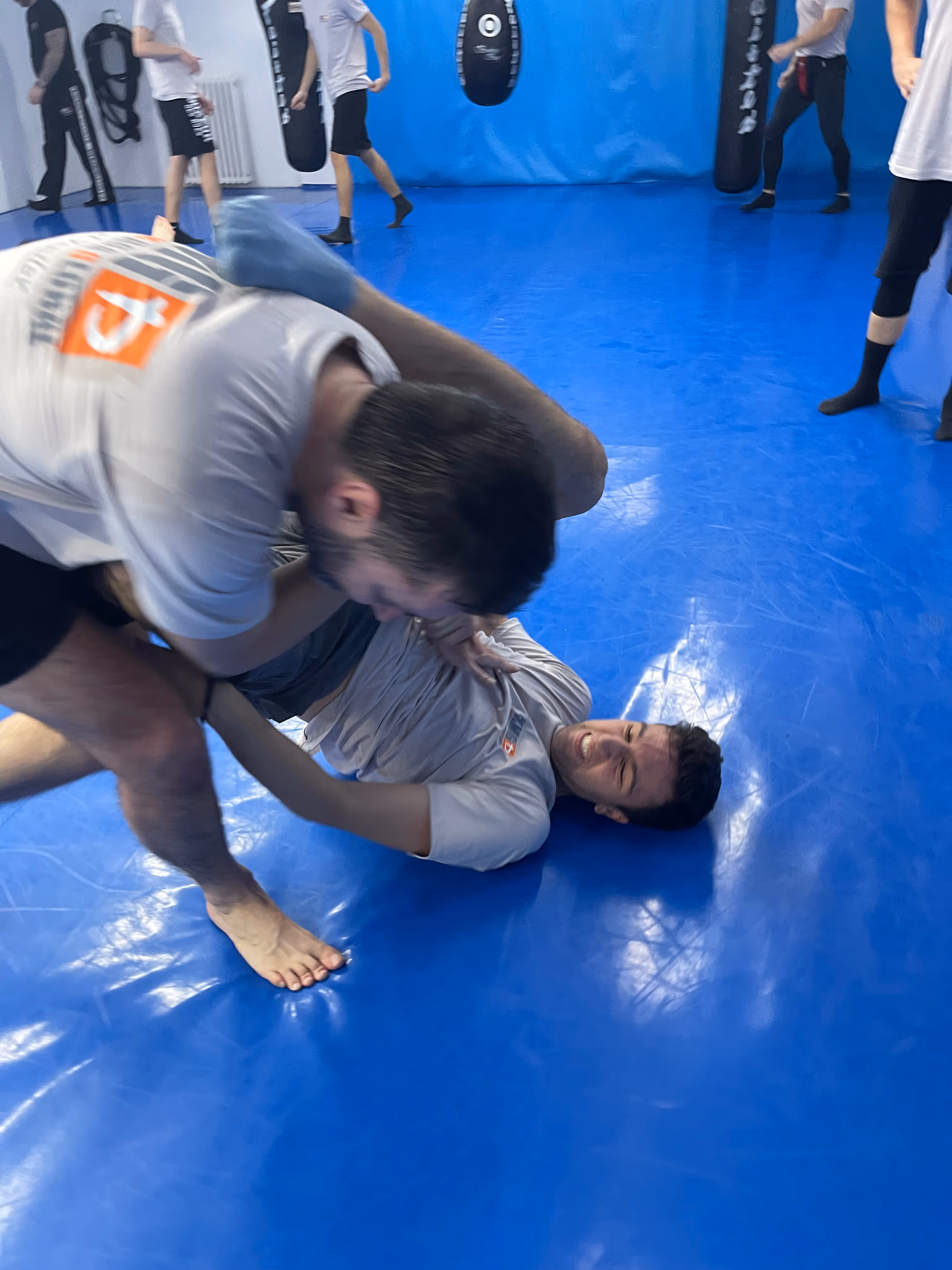 Polaznici Krav Maga treninga demonstriraju tehnike tokom testiranja za P nivo u sali, pod nadzorom instruktora