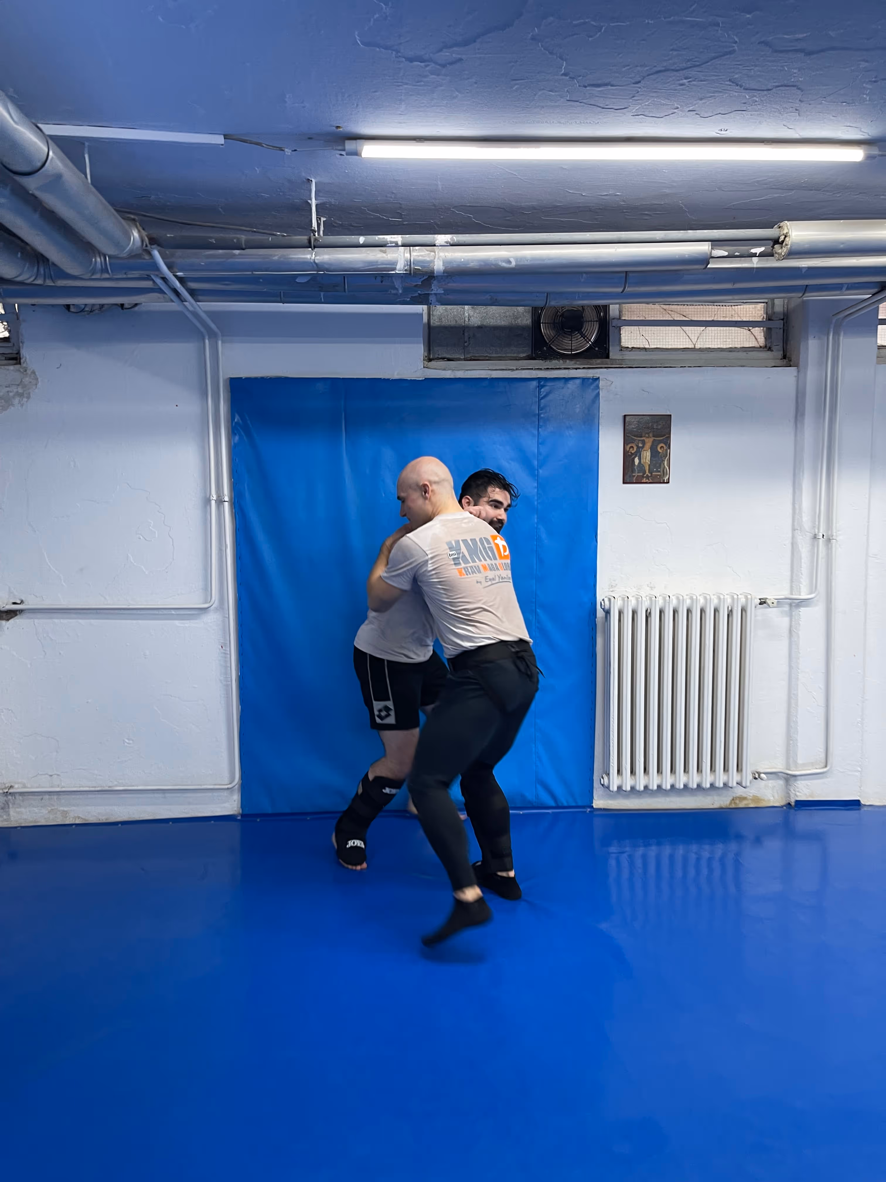Polaznici Krav Maga treninga demonstriraju tehnike tokom testiranja za P nivo u sali, pod nadzorom instruktora