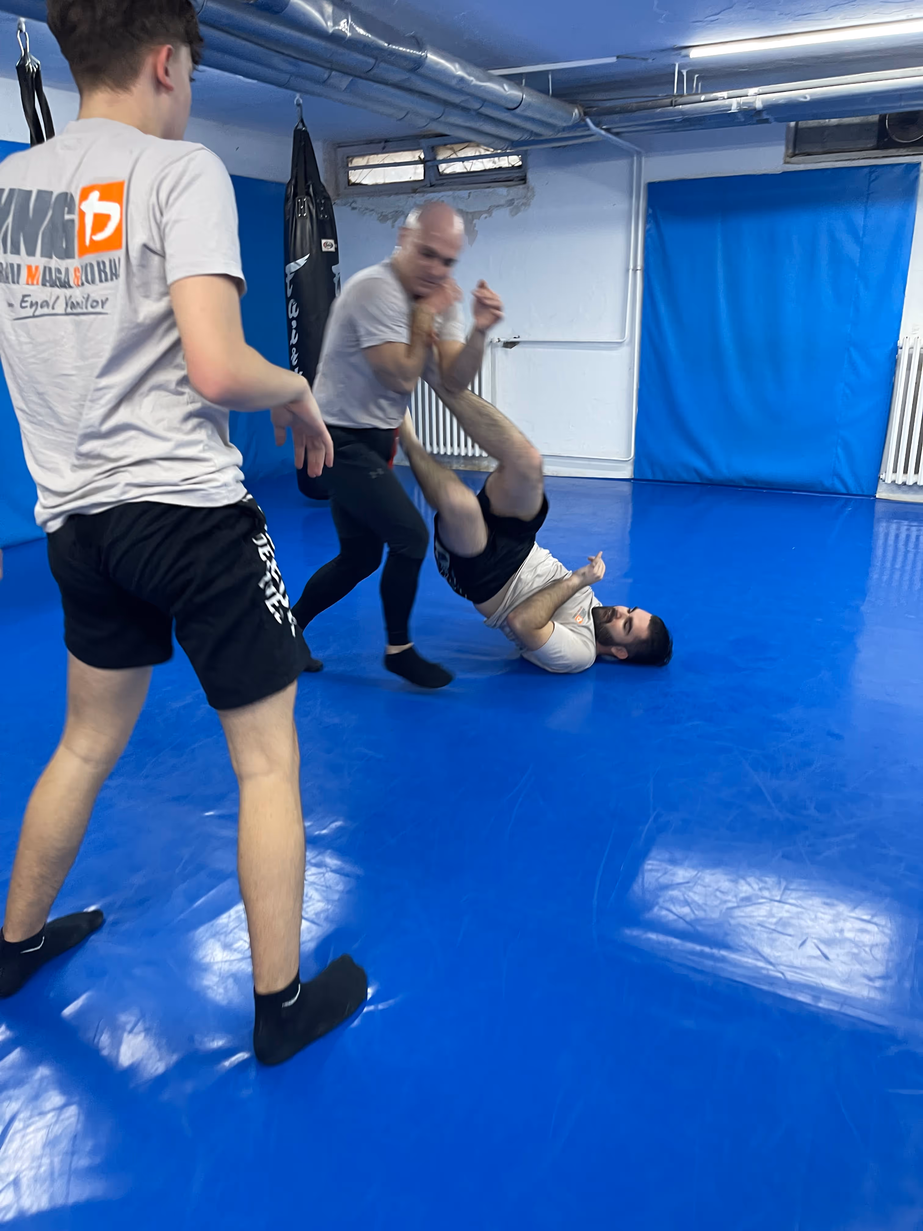 Polaznici Krav Maga treninga demonstriraju tehnike tokom testiranja za P nivo u sali, pod nadzorom instruktora