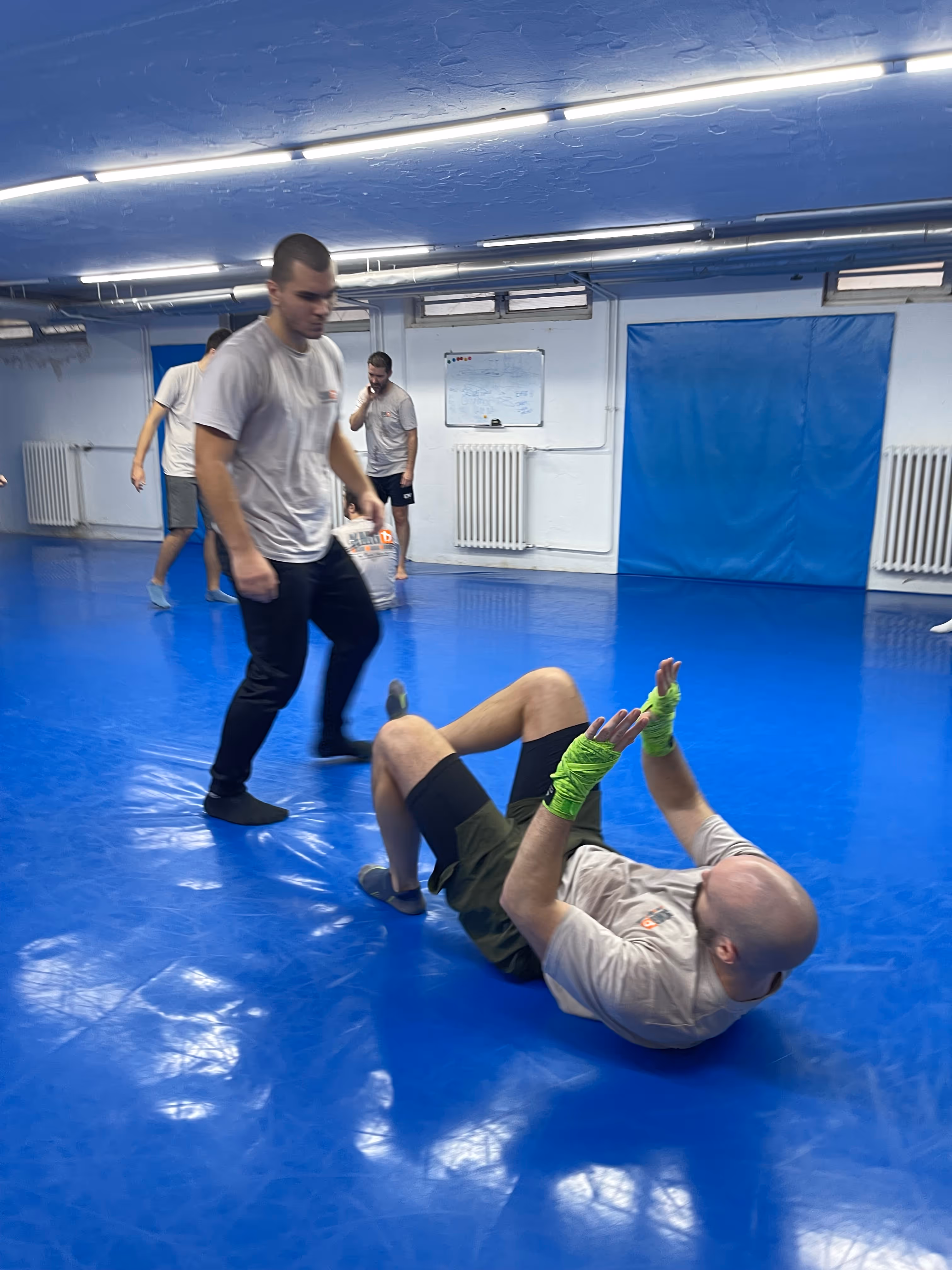 Polaznici Krav Maga treninga demonstriraju tehnike tokom testiranja za P nivo u sali, pod nadzorom instruktora