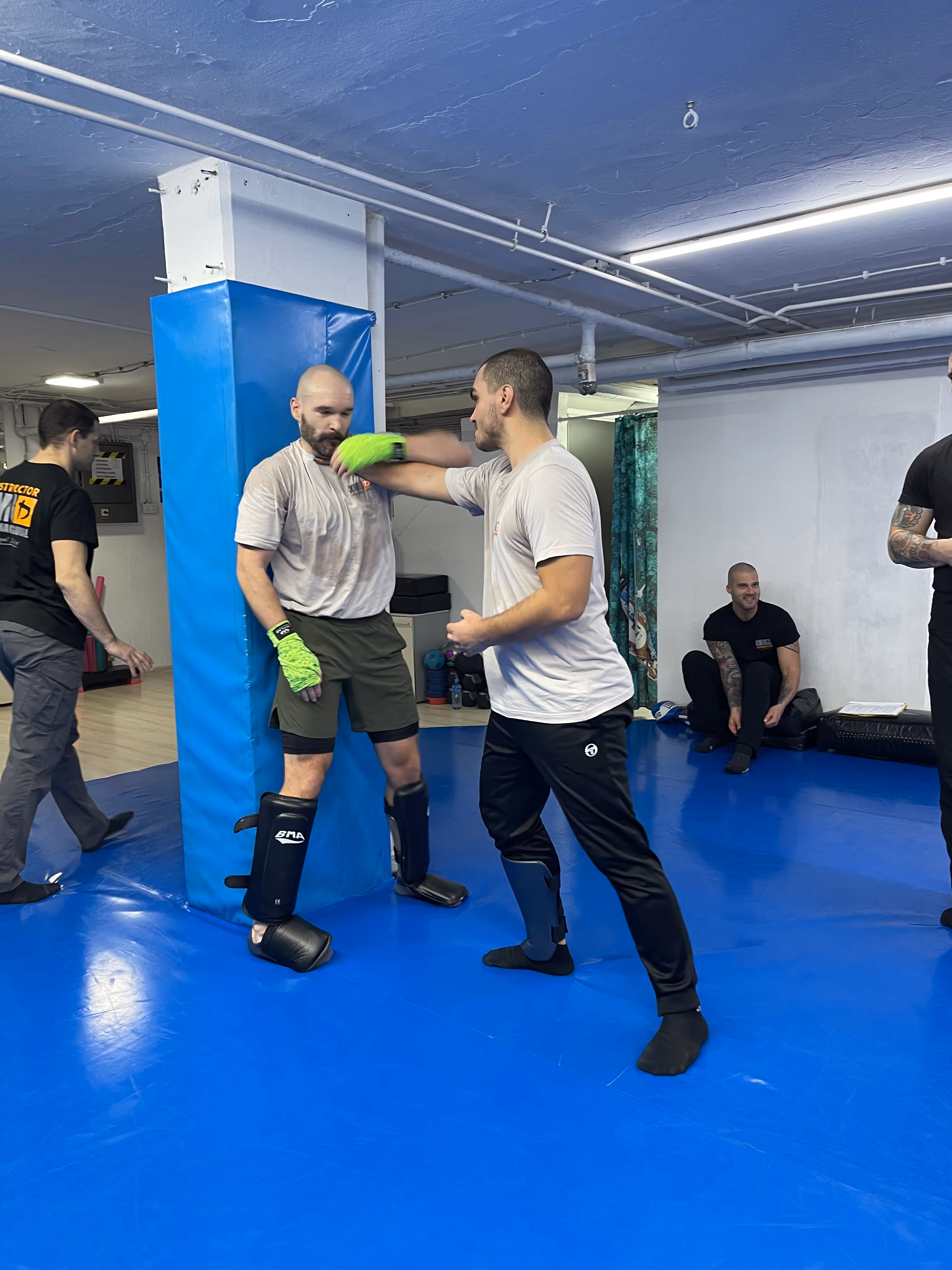 Polaznici Krav Maga treninga demonstriraju tehnike tokom testiranja za P nivo u sali, pod nadzorom instruktora