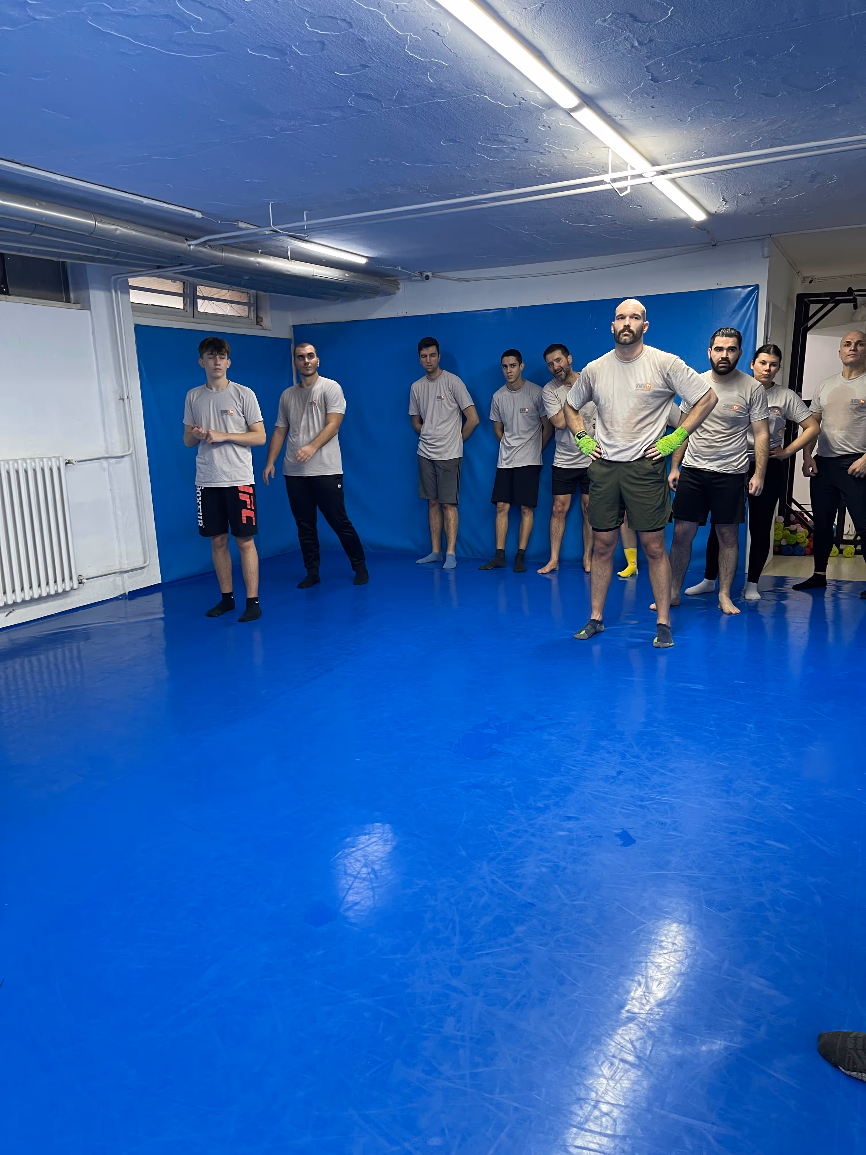 Polaznici Krav Maga treninga demonstriraju tehnike tokom testiranja za P nivo u sali, pod nadzorom instruktora