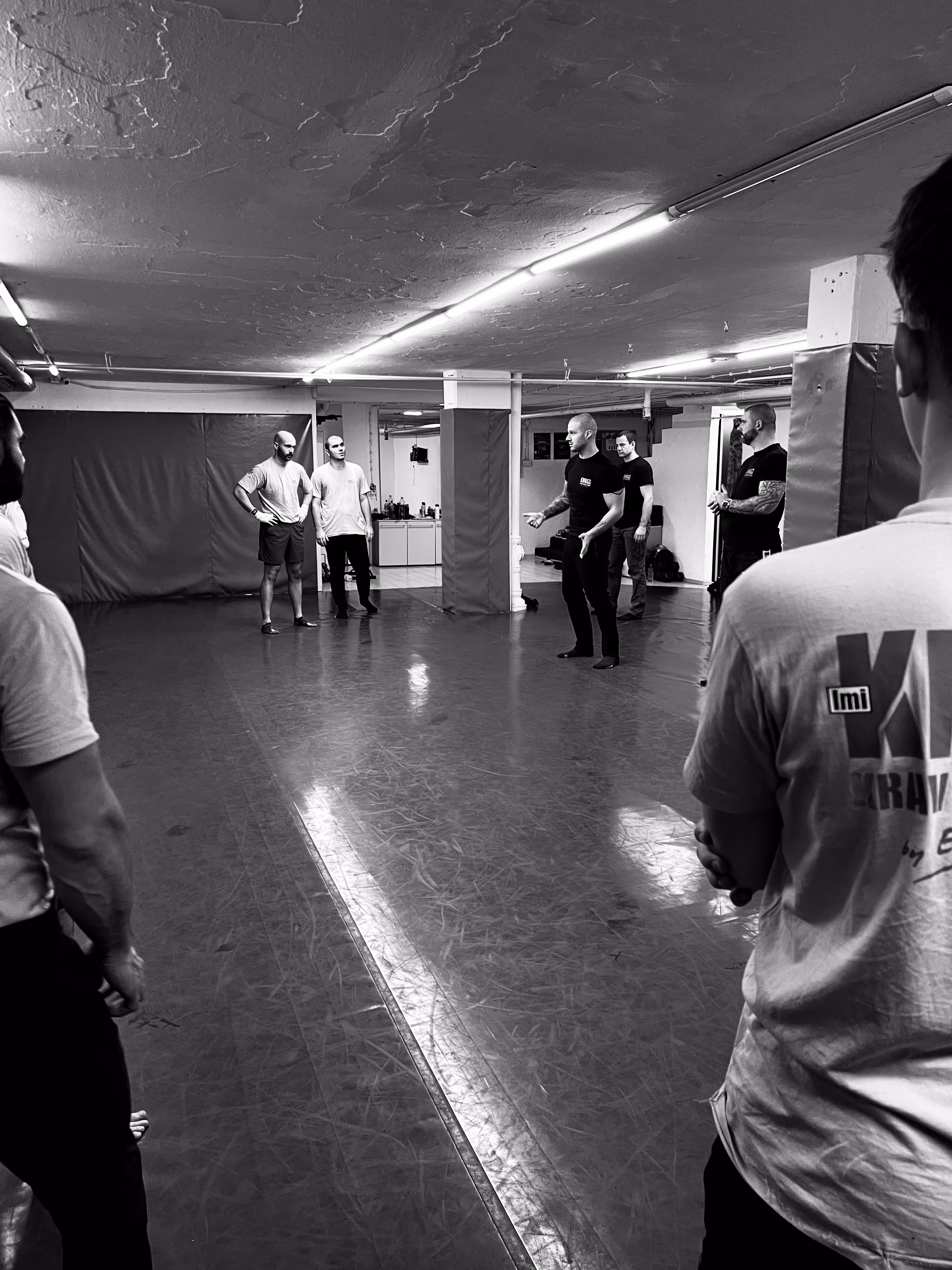 Polaznici Krav Maga treninga demonstriraju tehnike tokom testiranja za P nivo u sali, pod nadzorom instruktora