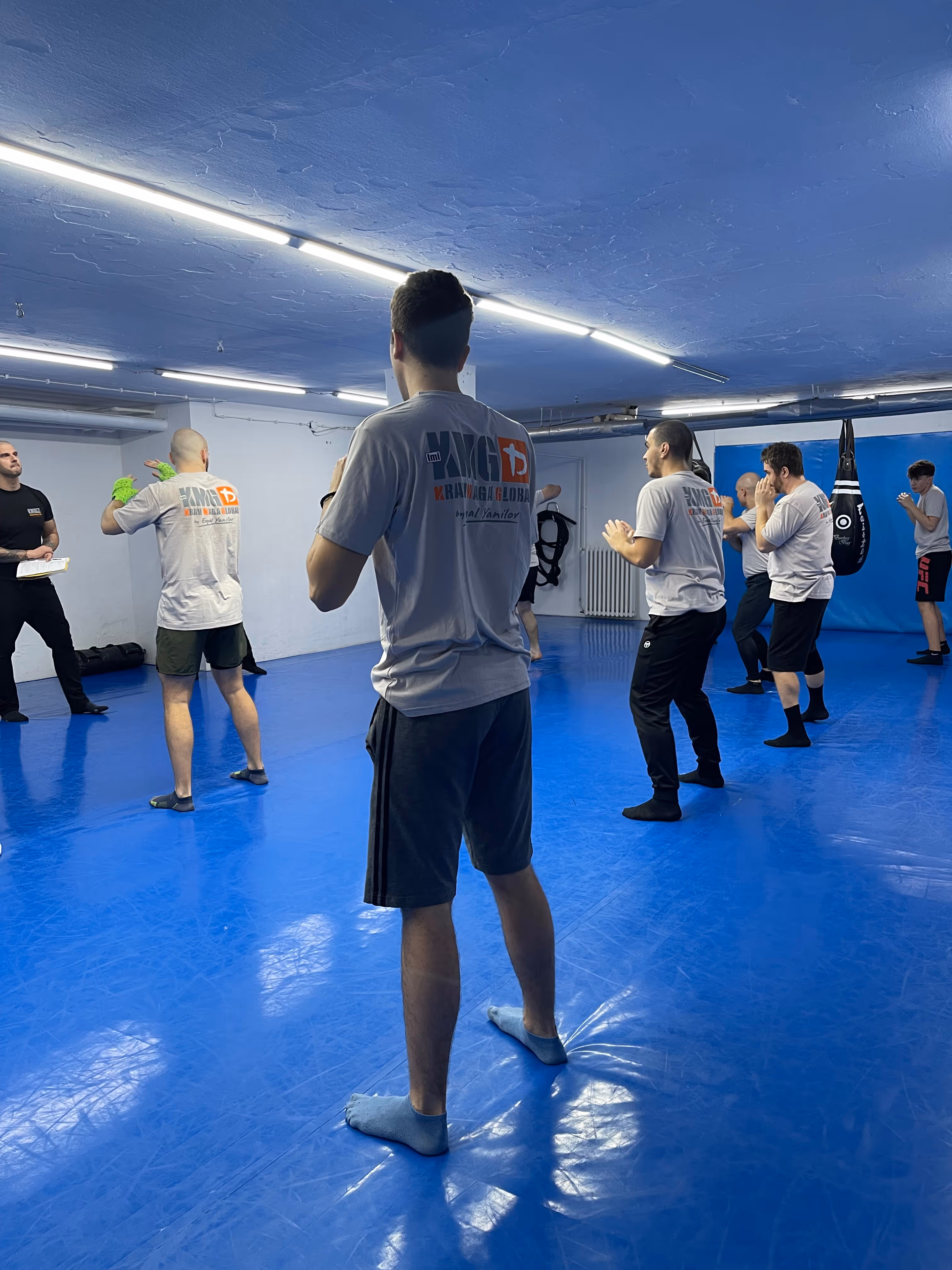 Polaznici Krav Maga treninga demonstriraju tehnike tokom testiranja za P nivo u sali, pod nadzorom instruktora