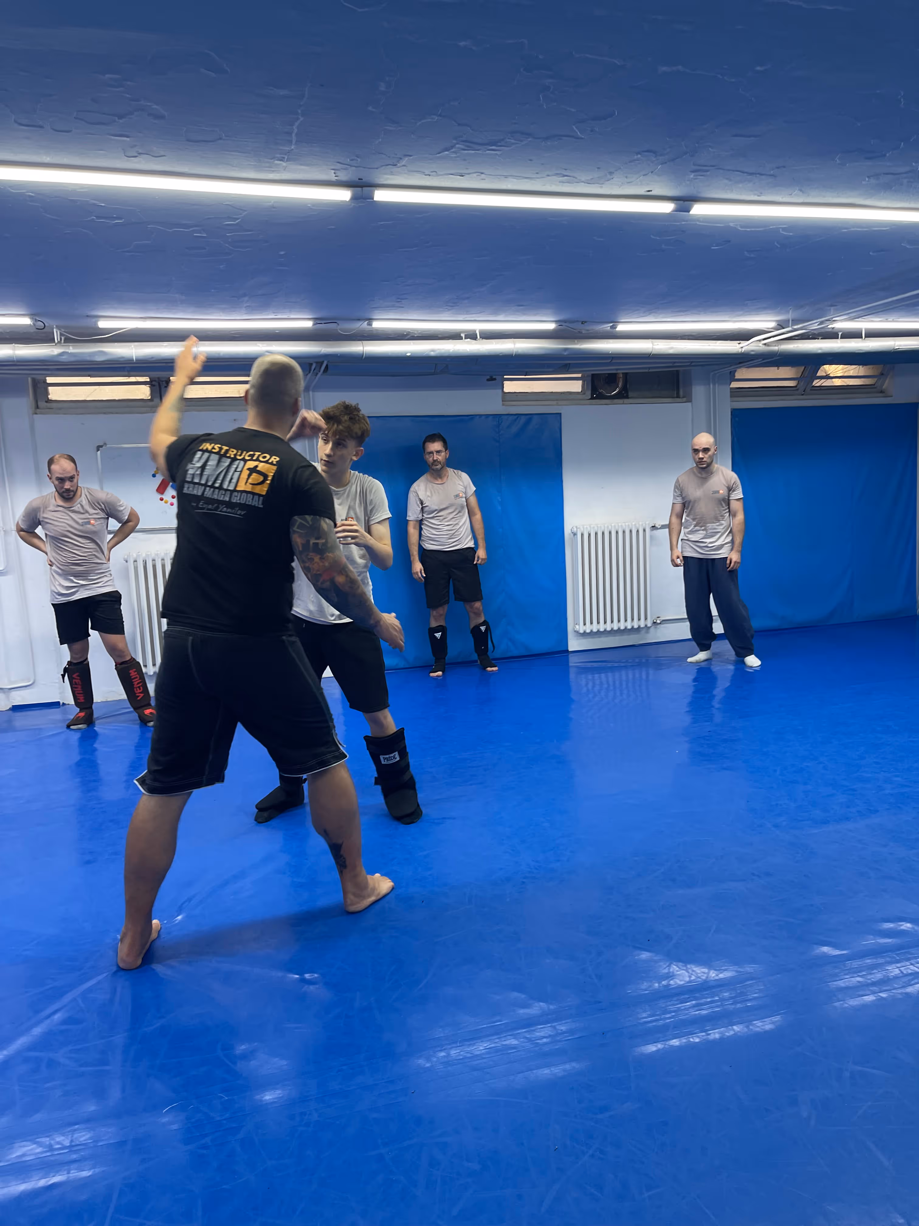 Polaznici Krav Maga treninga demonstriraju tehnike tokom testiranja za P nivo u sali, pod nadzorom instruktora