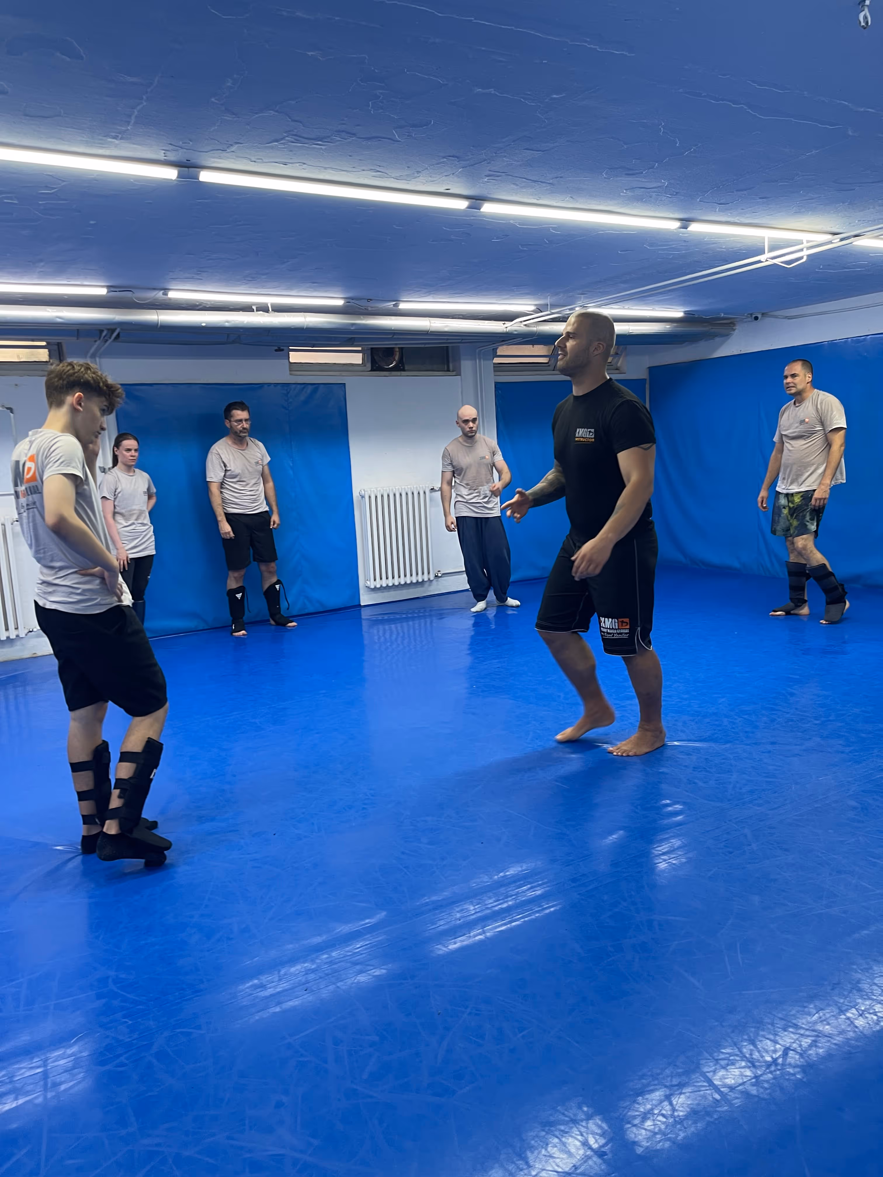 Polaznici Krav Maga treninga demonstriraju tehnike tokom testiranja za P nivo u sali, pod nadzorom instruktora