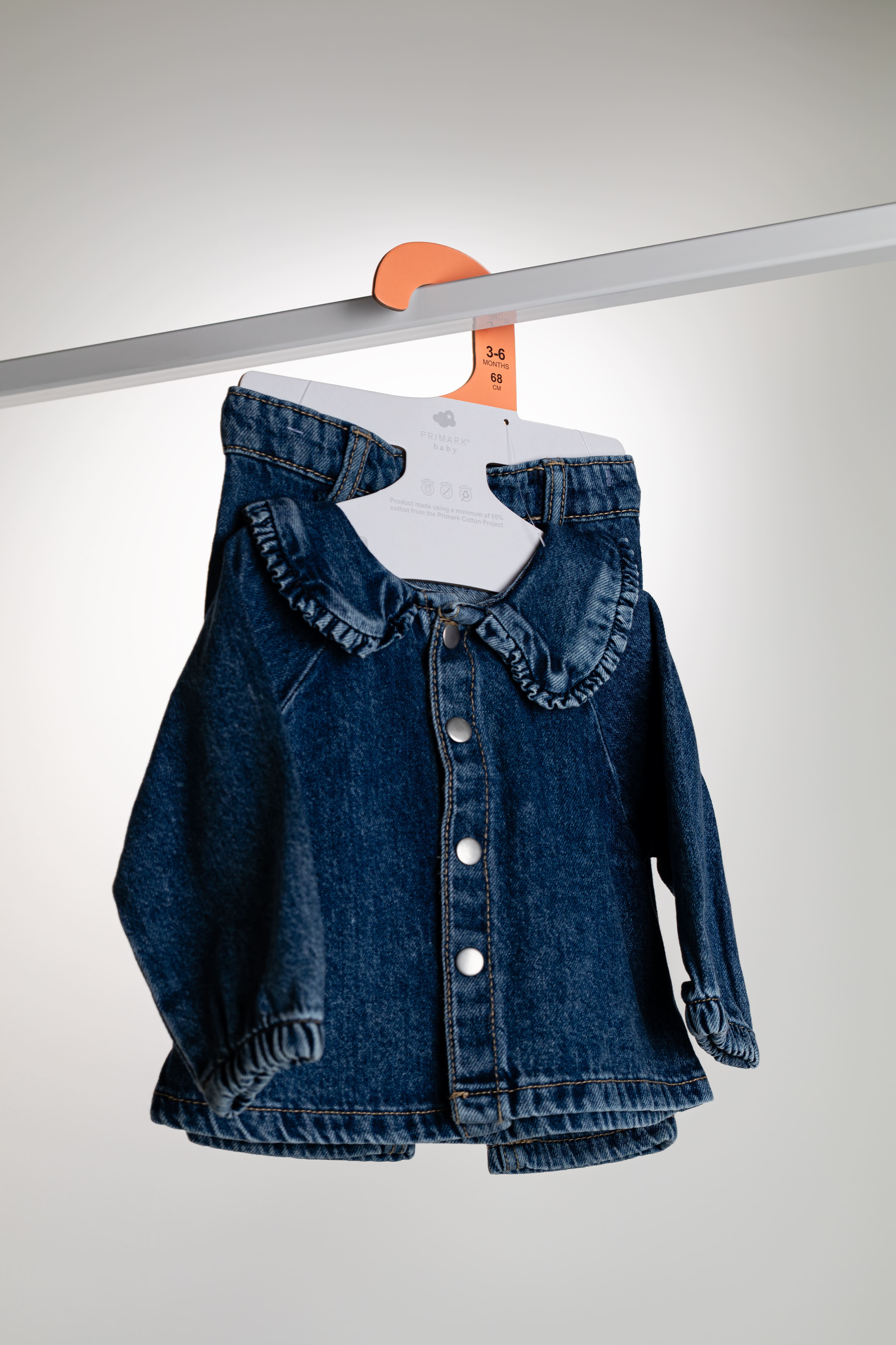 Custom paper hanger designed for babywear, displaying a coordinated dark blue denim jacket with ruffled collar and matching leggings.