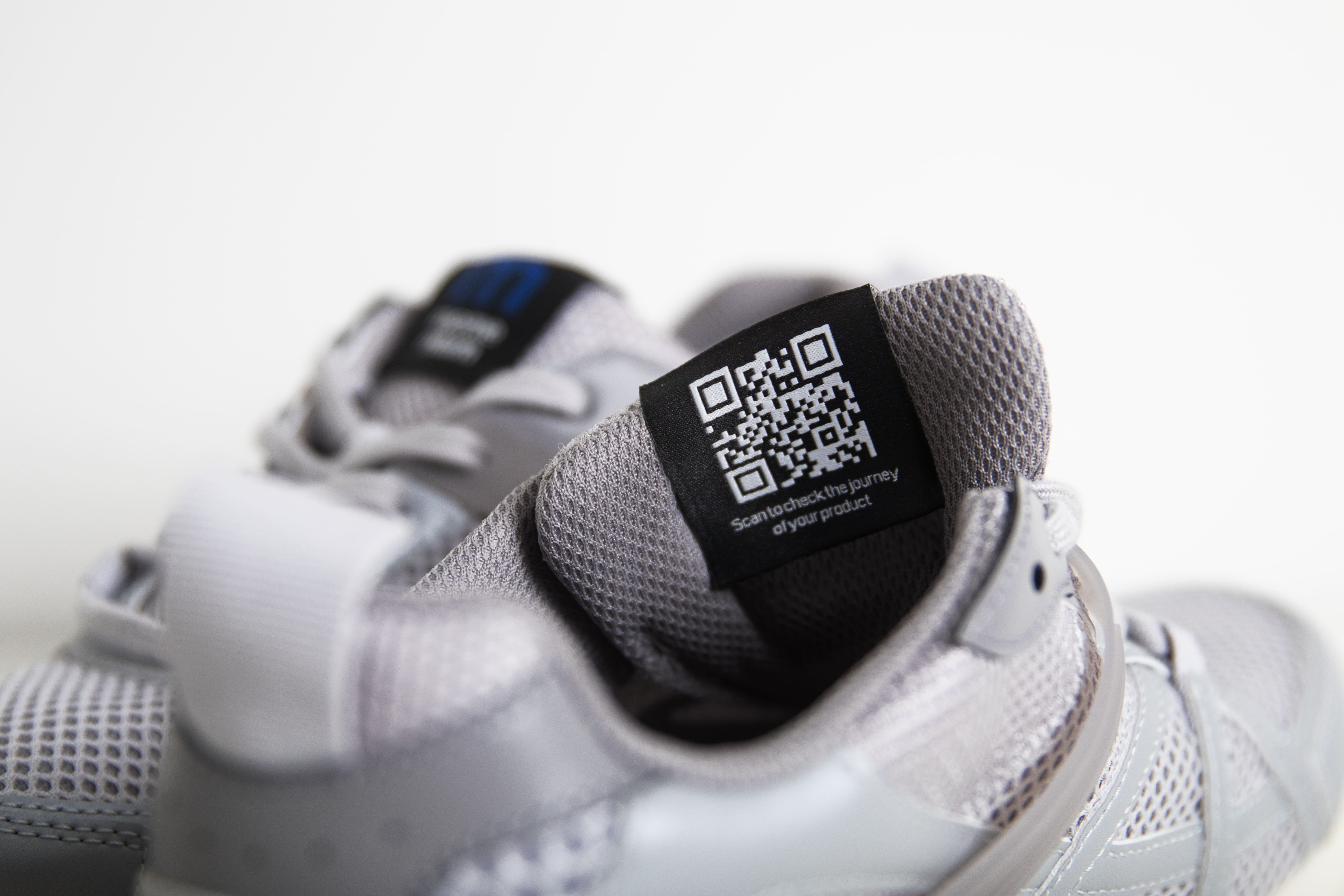 Close-up of athletic sneakers featuring a black QR code label on the tongue, combining performance footwear with digital product identification.
