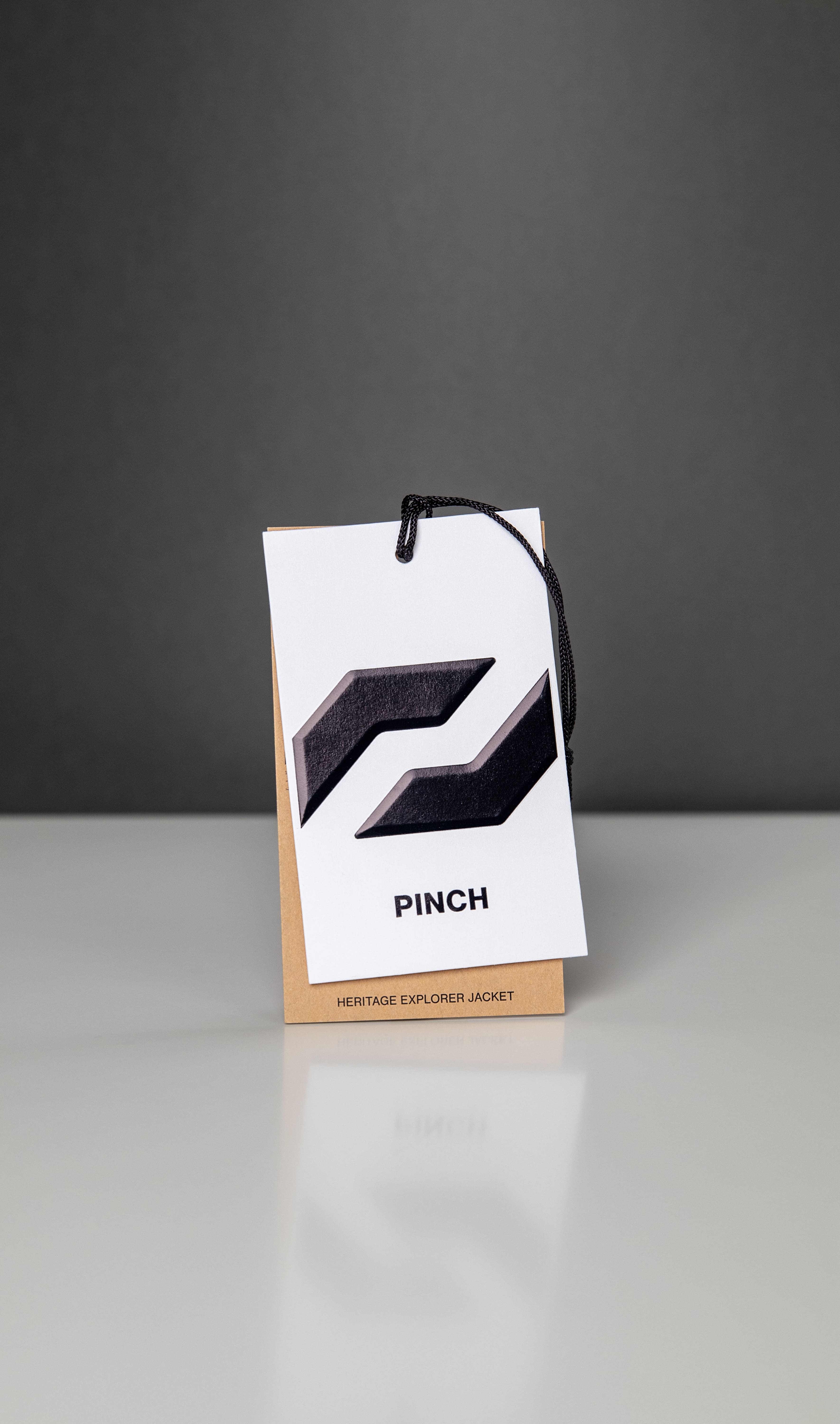 A black and white hang tag featuring the word “PINCH” in bold lettering