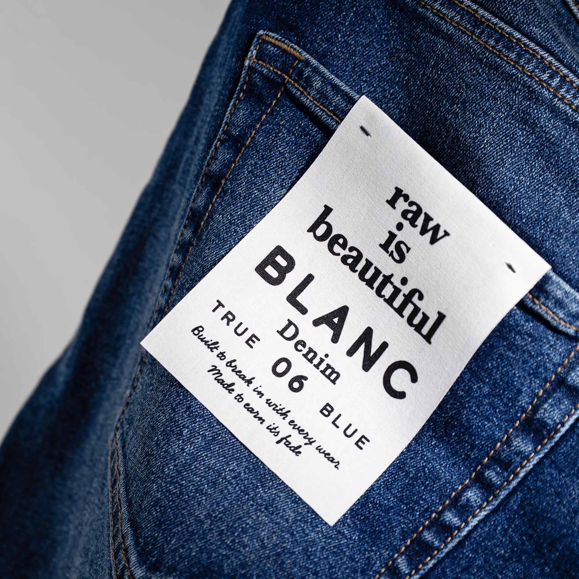 Close-up of a premium denim jacket featuring a glossy "Pinch" logo on a branded hem patch.