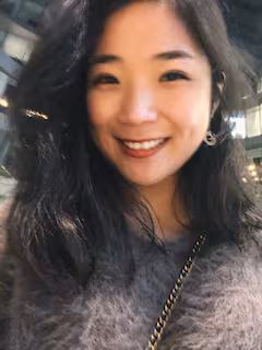 Two people kayaking on a calm lake with mountains in the background.