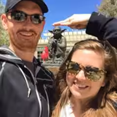 Two people kayaking on a calm lake with mountains in the background.