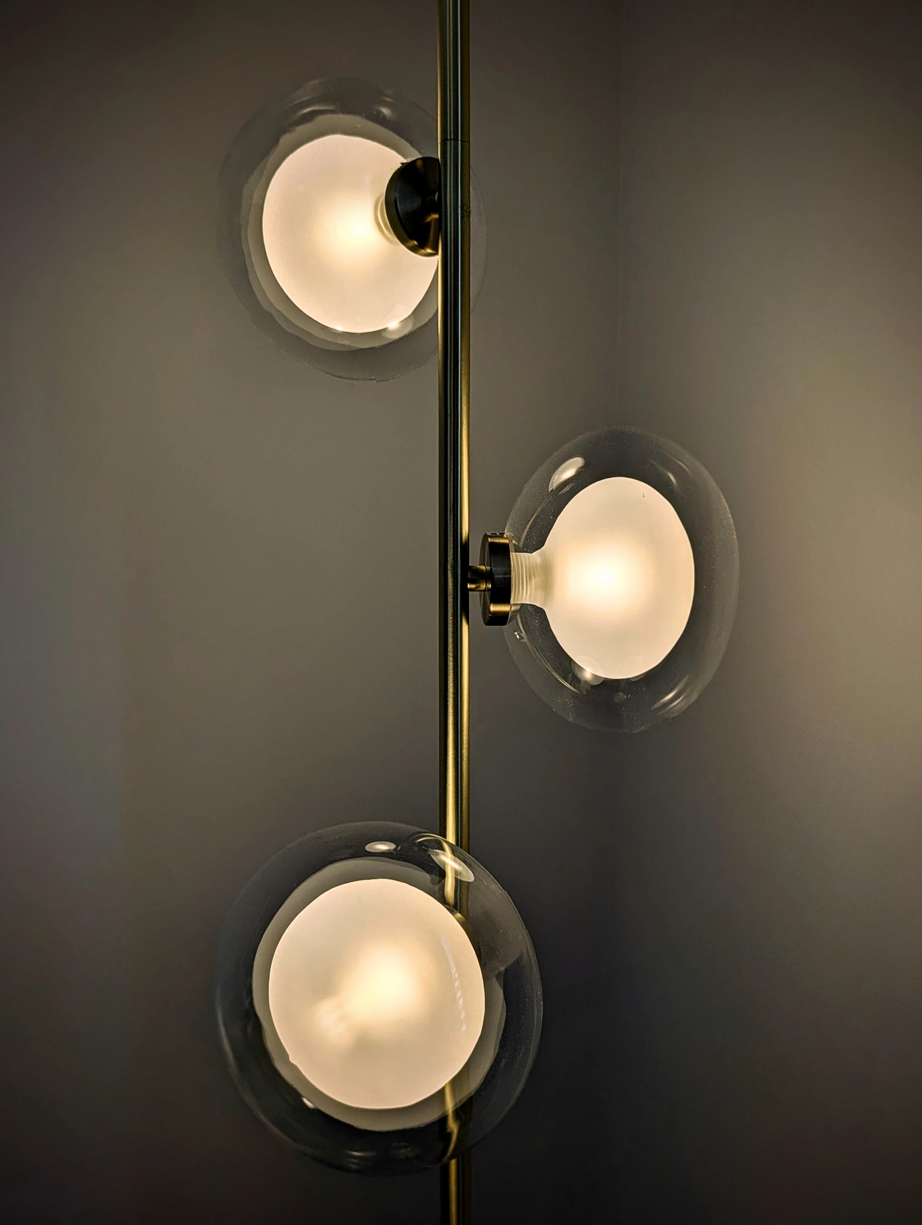 Lampadaire design structure laiton avec trois globes en verre transparent et diffuseurs internes blancs.