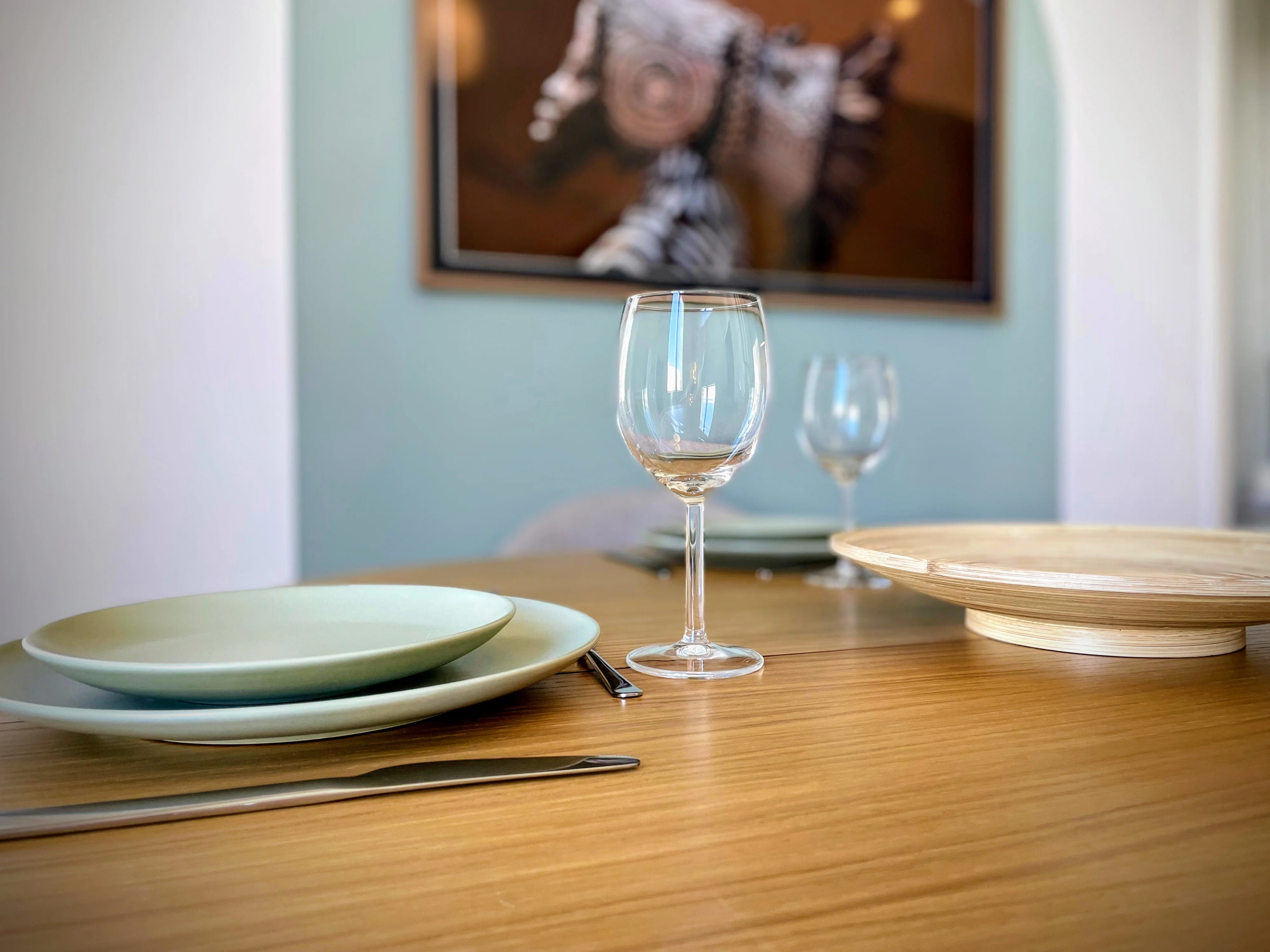 Gros plan verre à vin et assiettes en céramique vert d'eau sur table bois.
