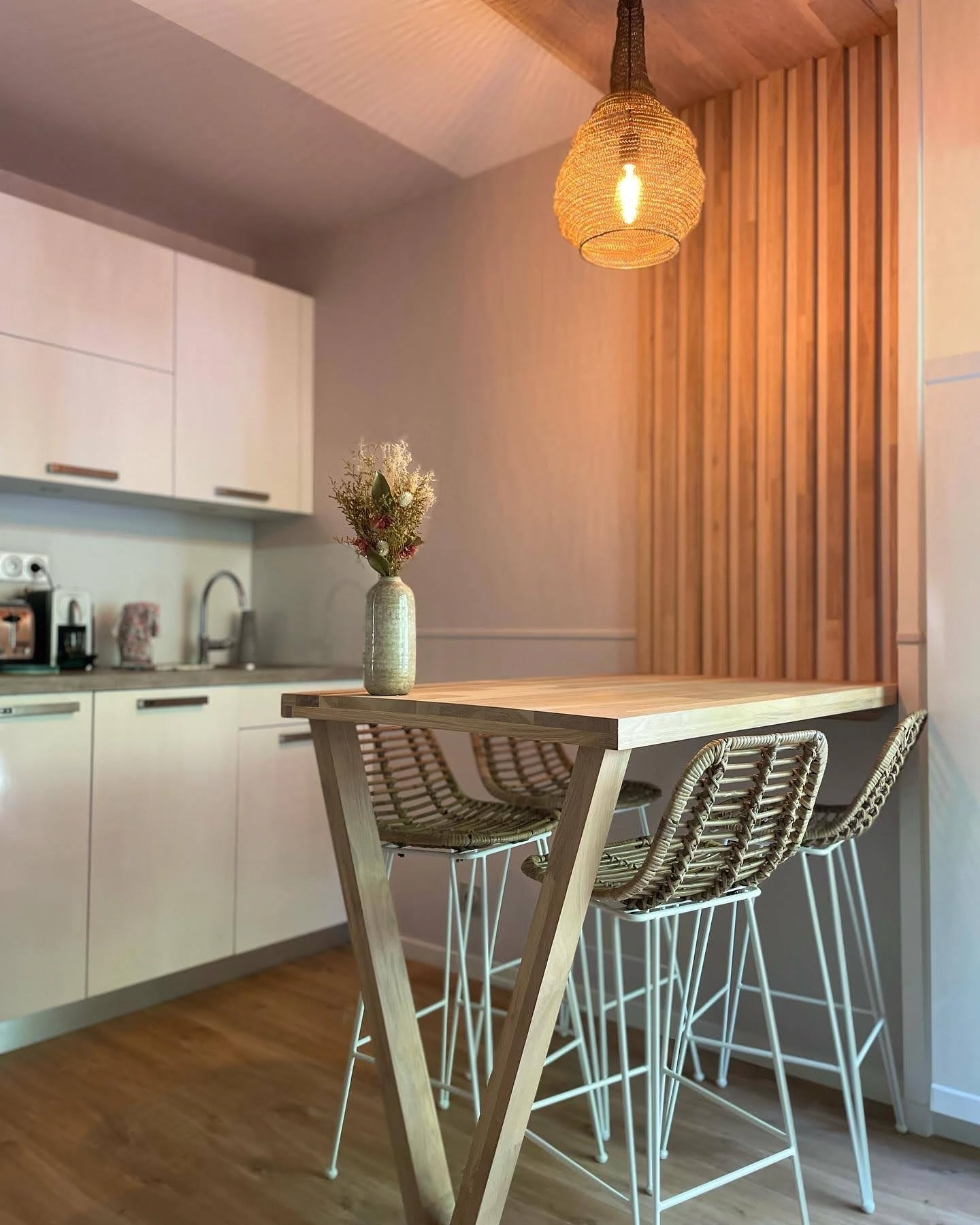 Table en bois sur mesure dans le coin cuisine d'un appartement rénové avec cuisine kitchenette en arrière plan