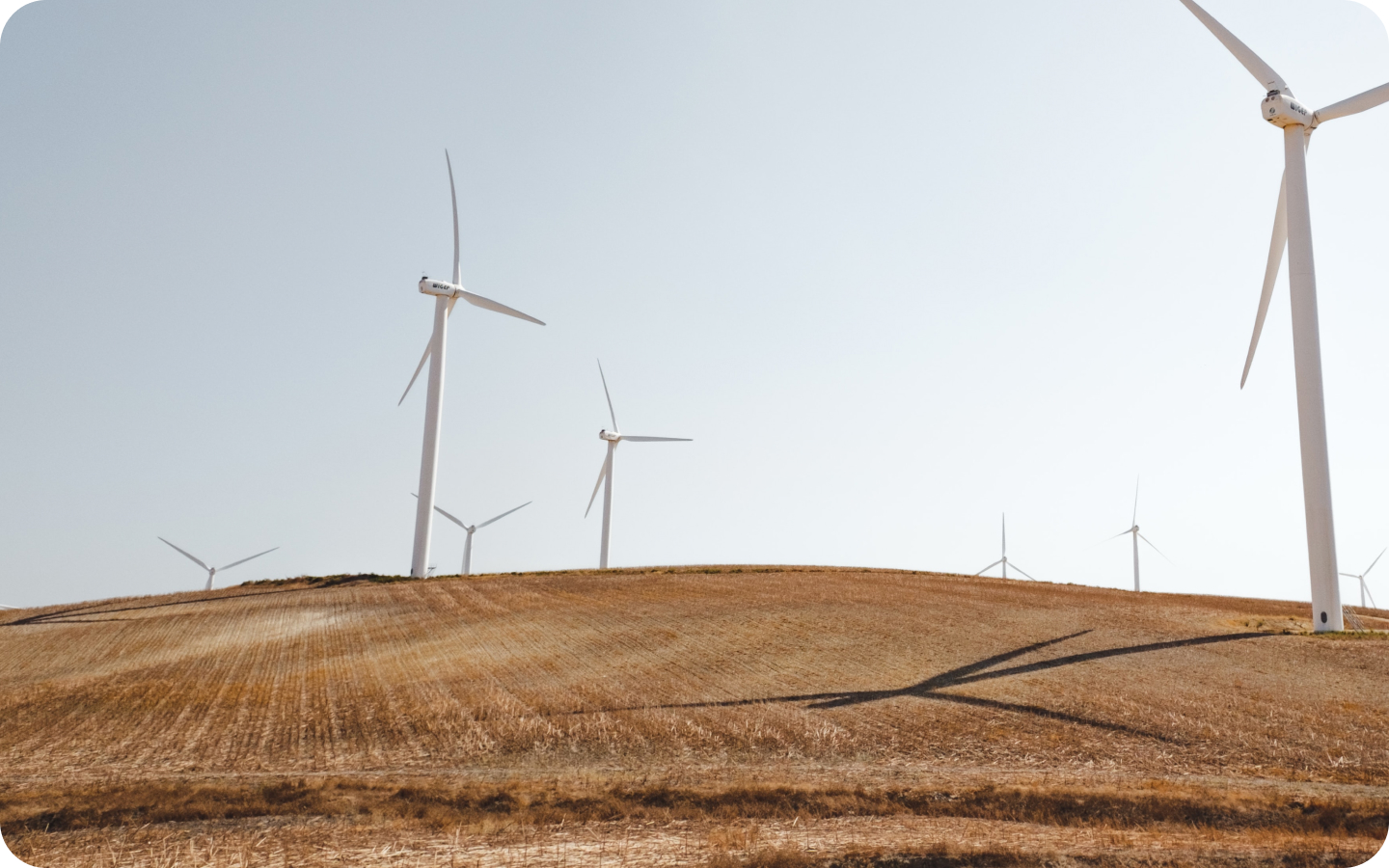 A photo of windmills over dirt land on a sunny day.