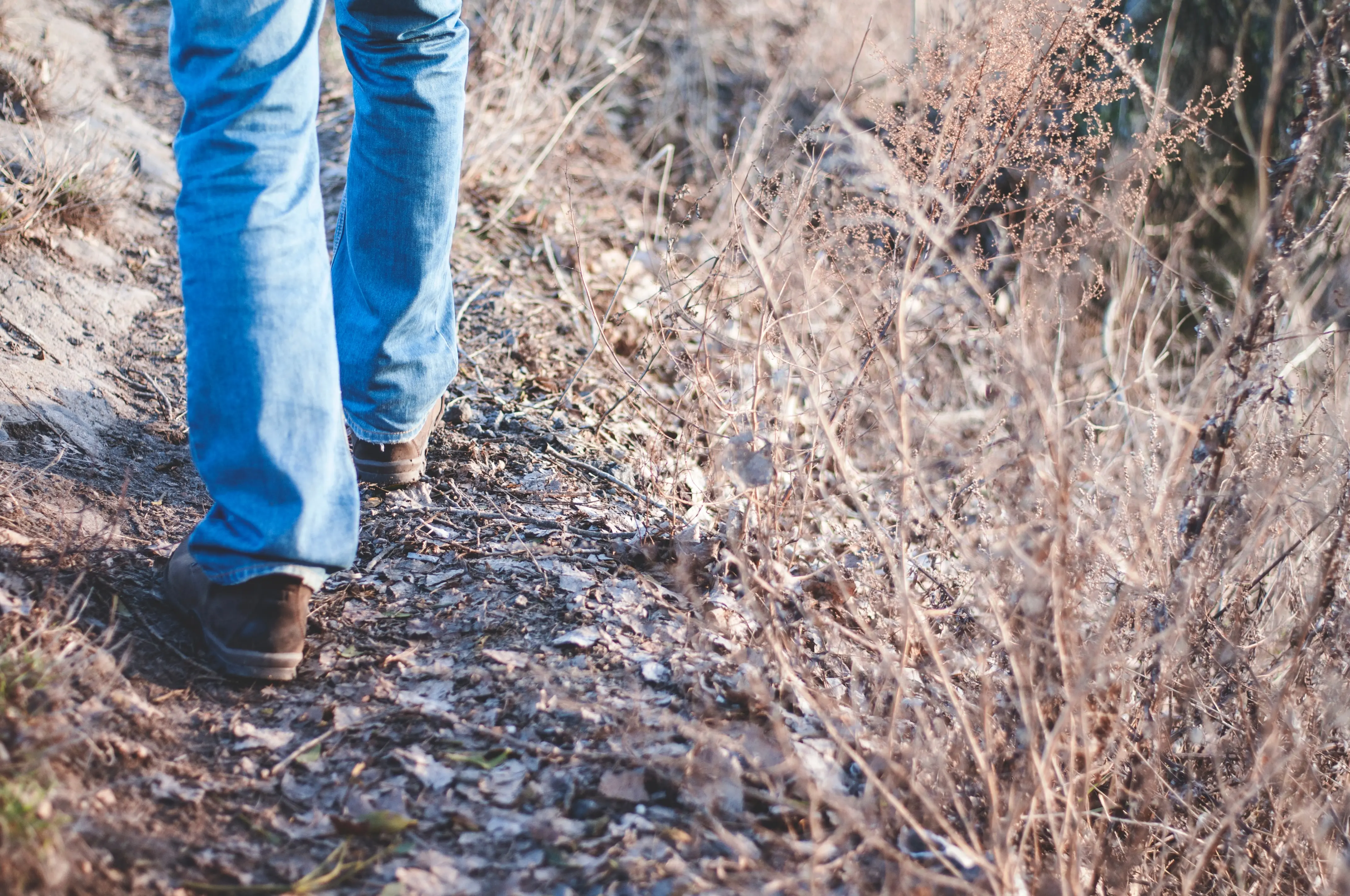 A person walking through trees with shoes and jeans