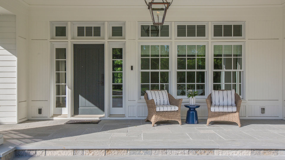 The front porch of a home with two wicker chairs