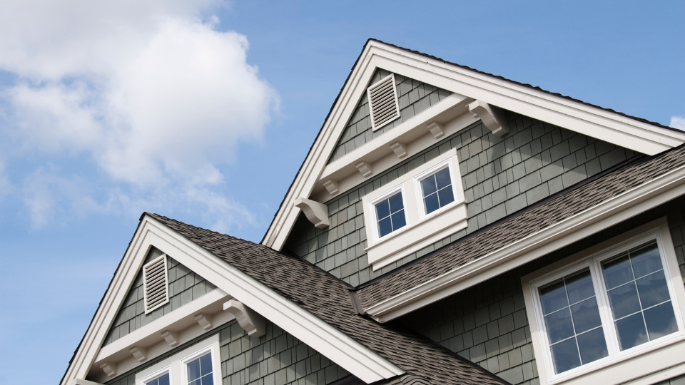 A house with gray siding and white trim against a blue sky
