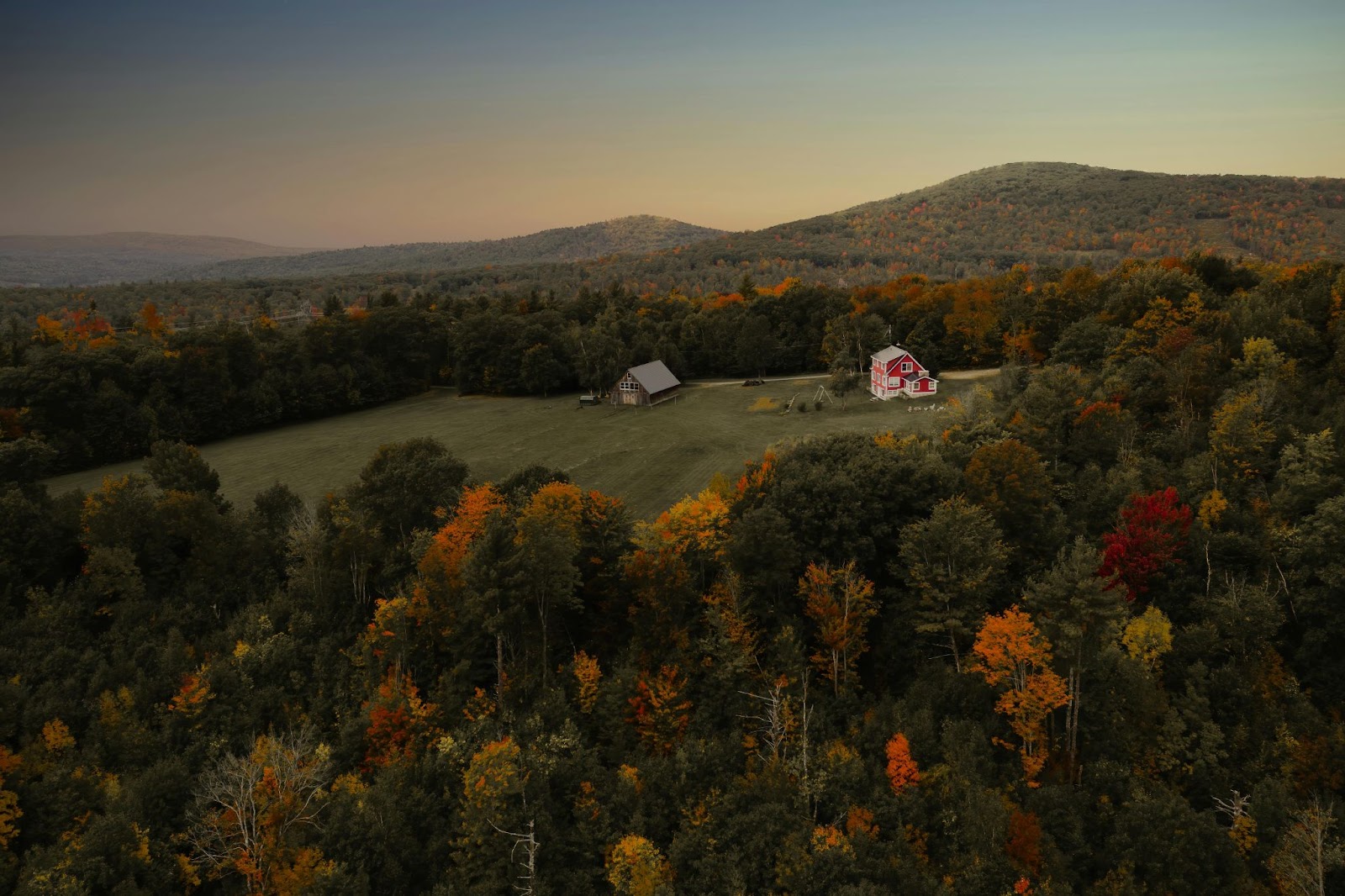 A red barn and a farmhouse settled on a large plot of land in the mountains
