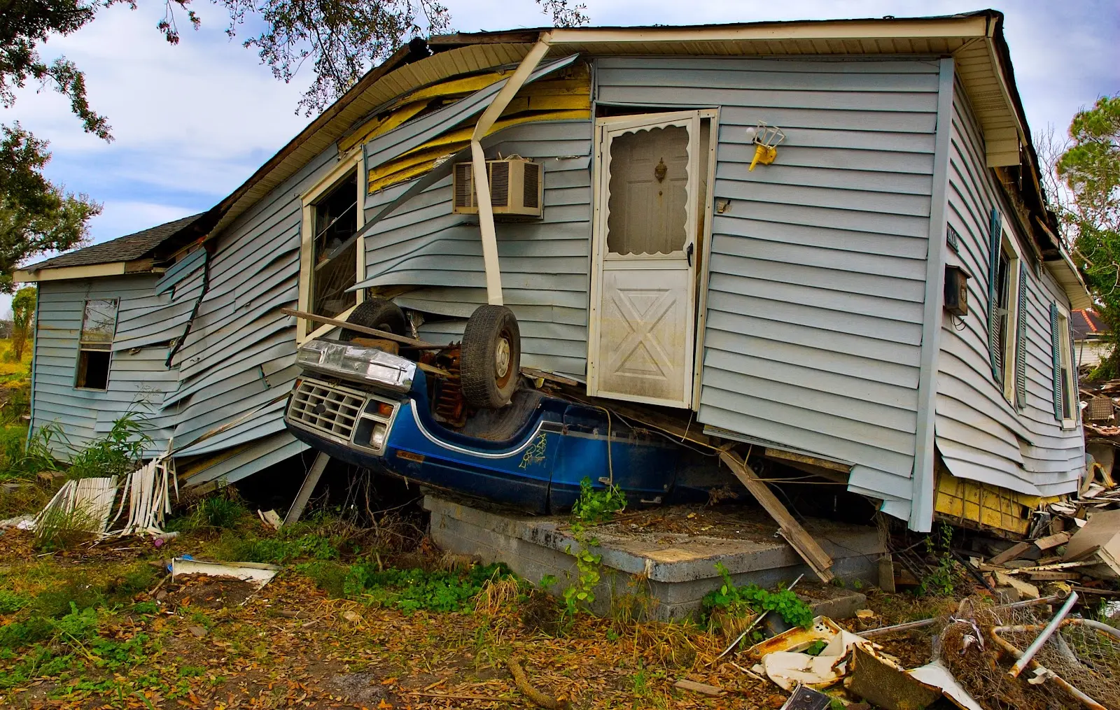 A flipped car under a home after a storm