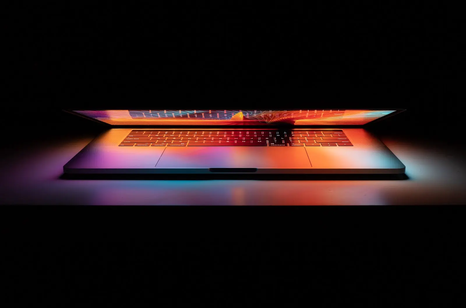 A laptop in a pitch black room on a desk