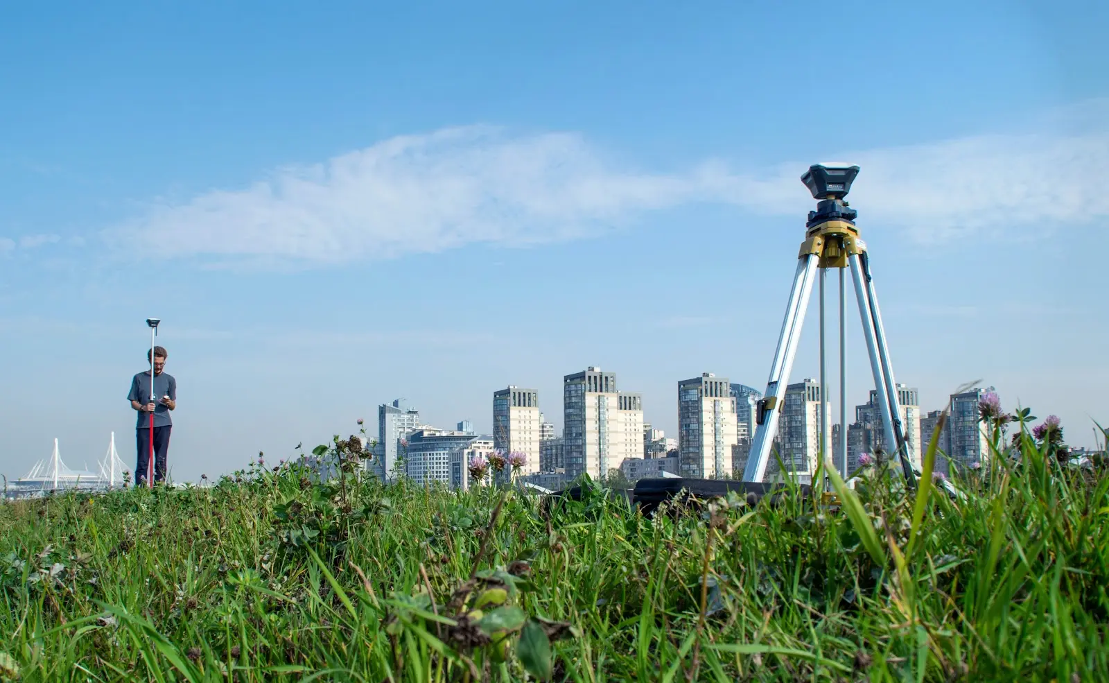 Man Surveying on open grass next to a big city