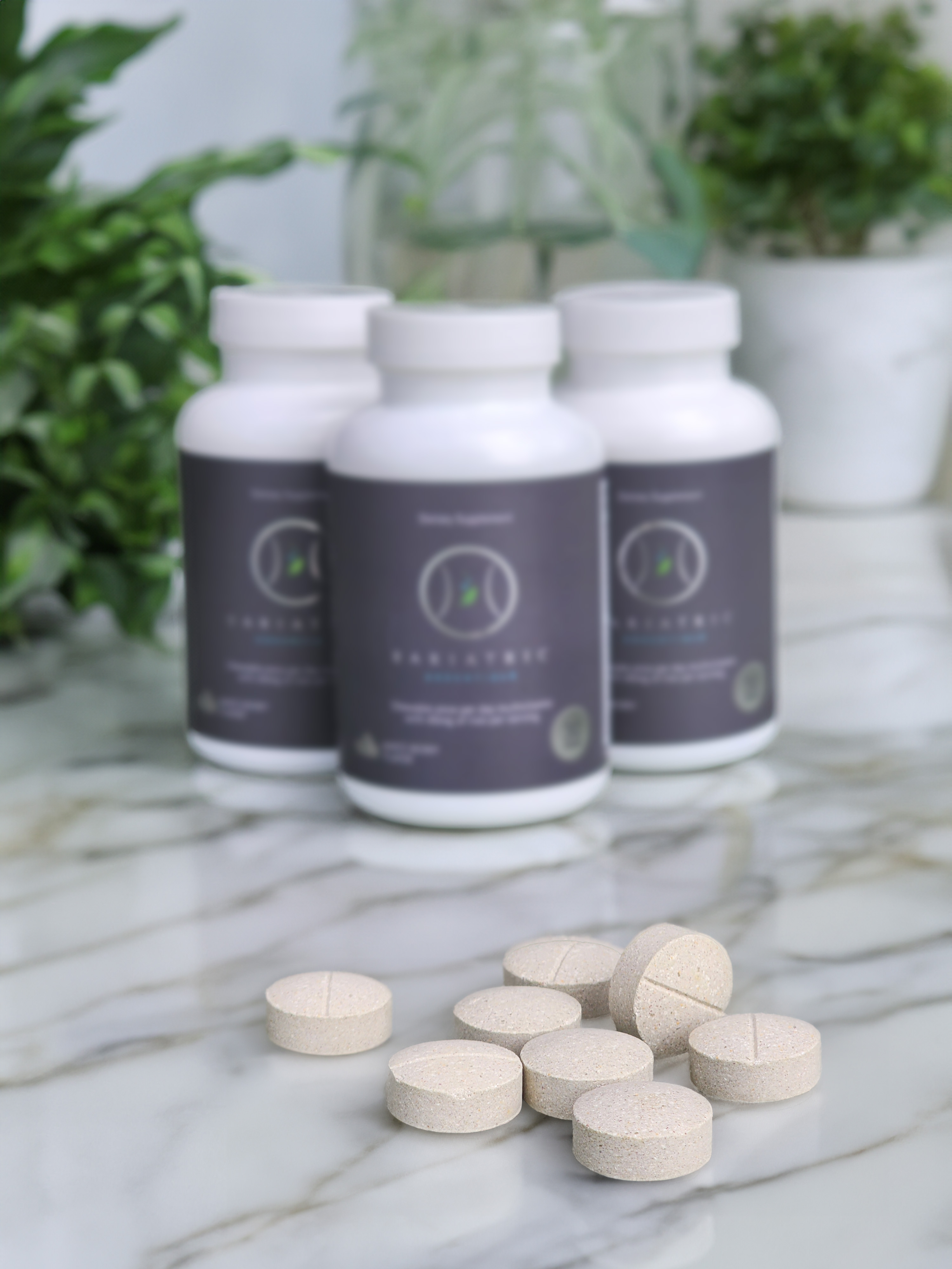 Three Bariatric Essentials bottles on marble with loose chewable tablets arranged in front.