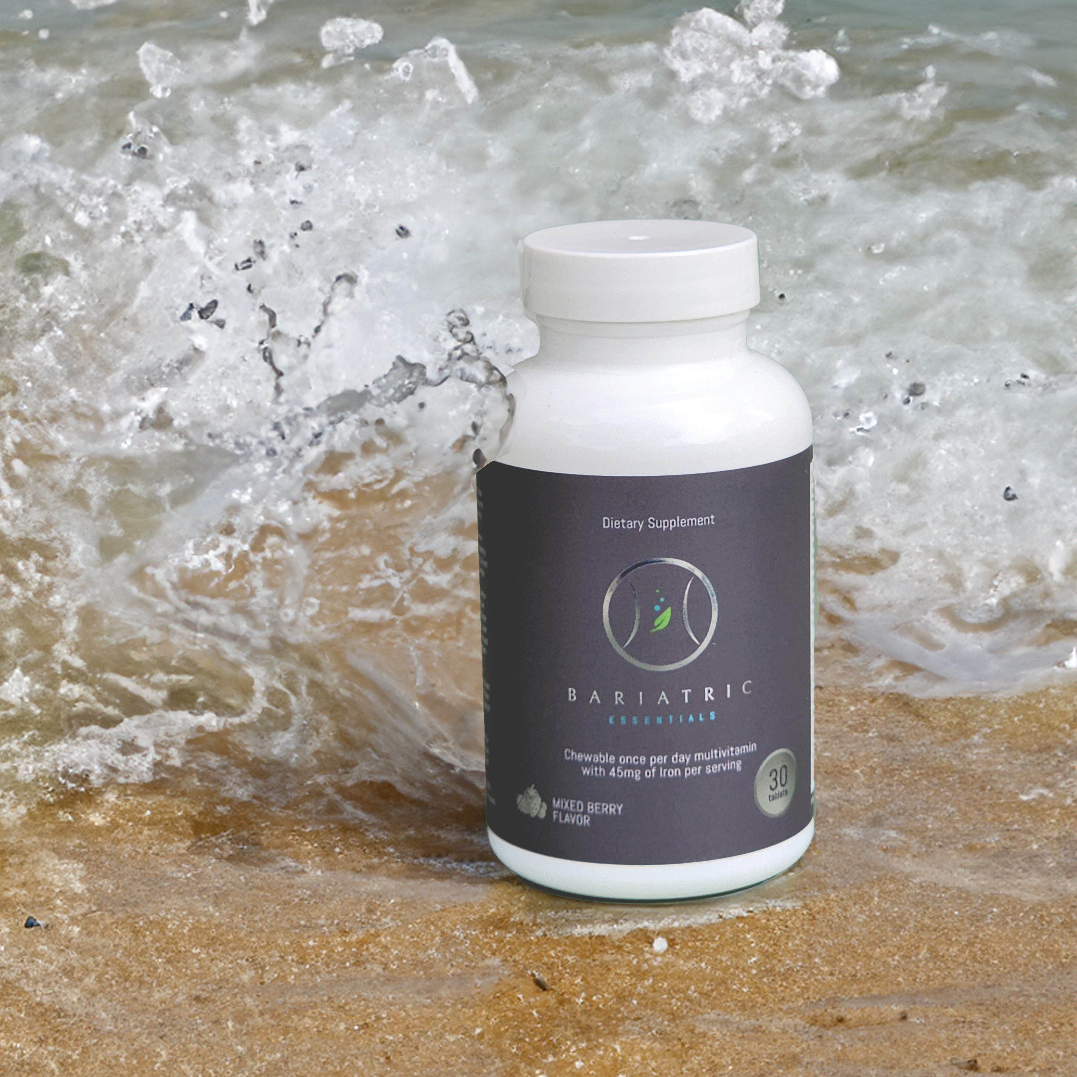 A Bariatric Essentials bottle photographed standing on wet sand as a wave breaks behind it.